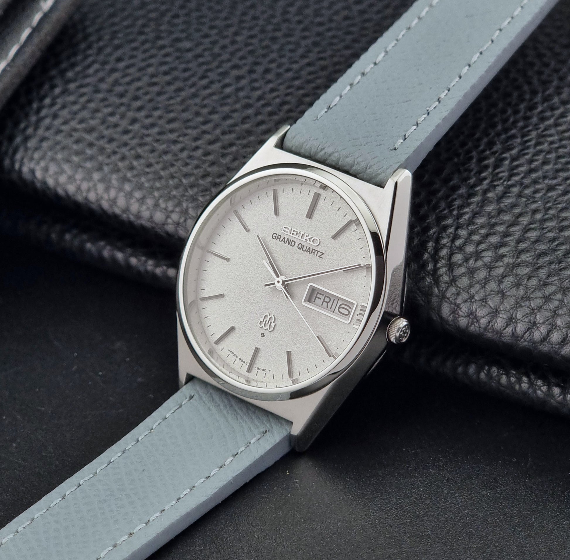 Vintage Seiko Grand Quartz watch 9943-8030 with a leather strap on a dark gray background crown view