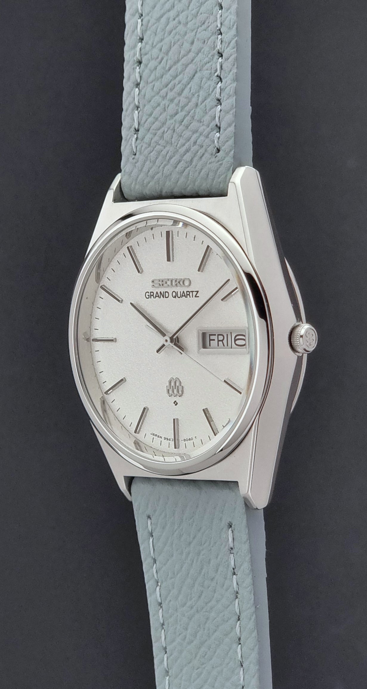 Vintage Seiko Grand Quartz watch 9943-8030 with a leather strap on a dark gray background crown profile view