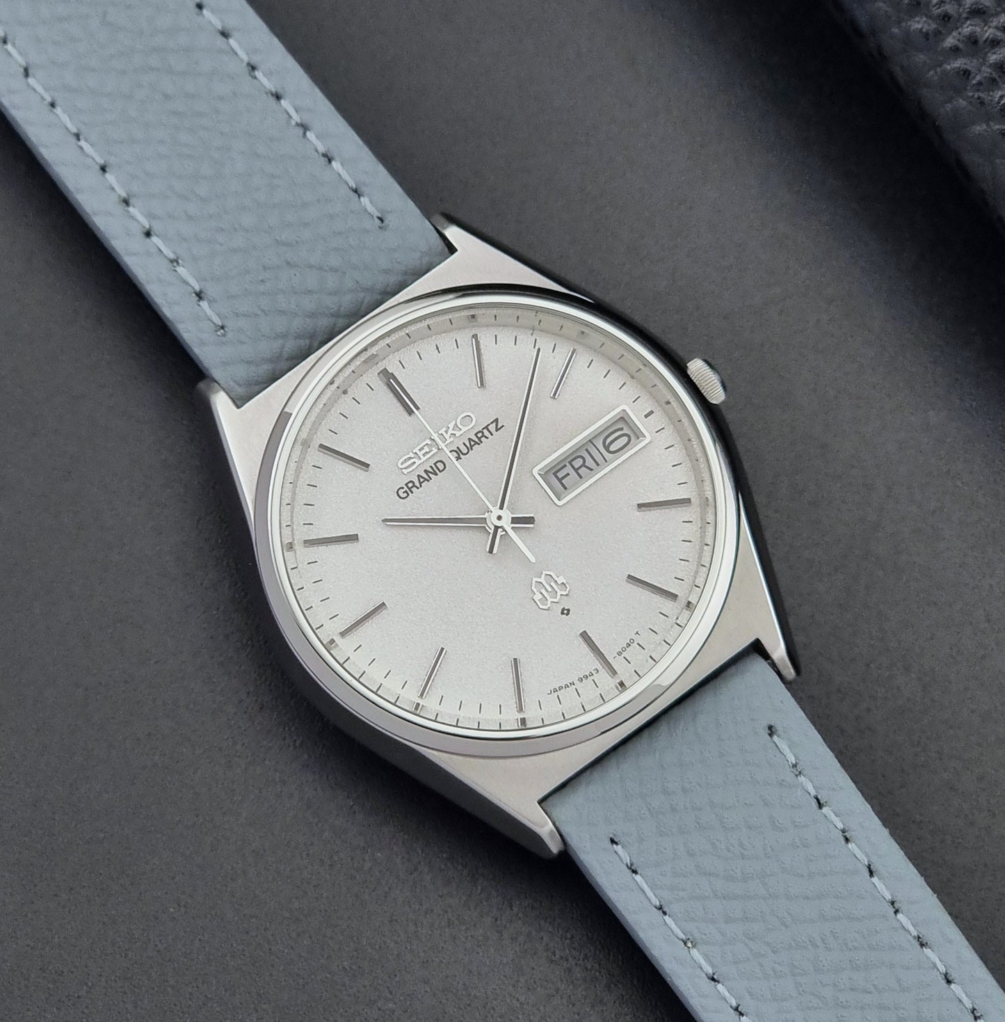 Vintage Seiko Grand Quartz watch 9943-8030 with a leather strap on a dark gray background close up dial view