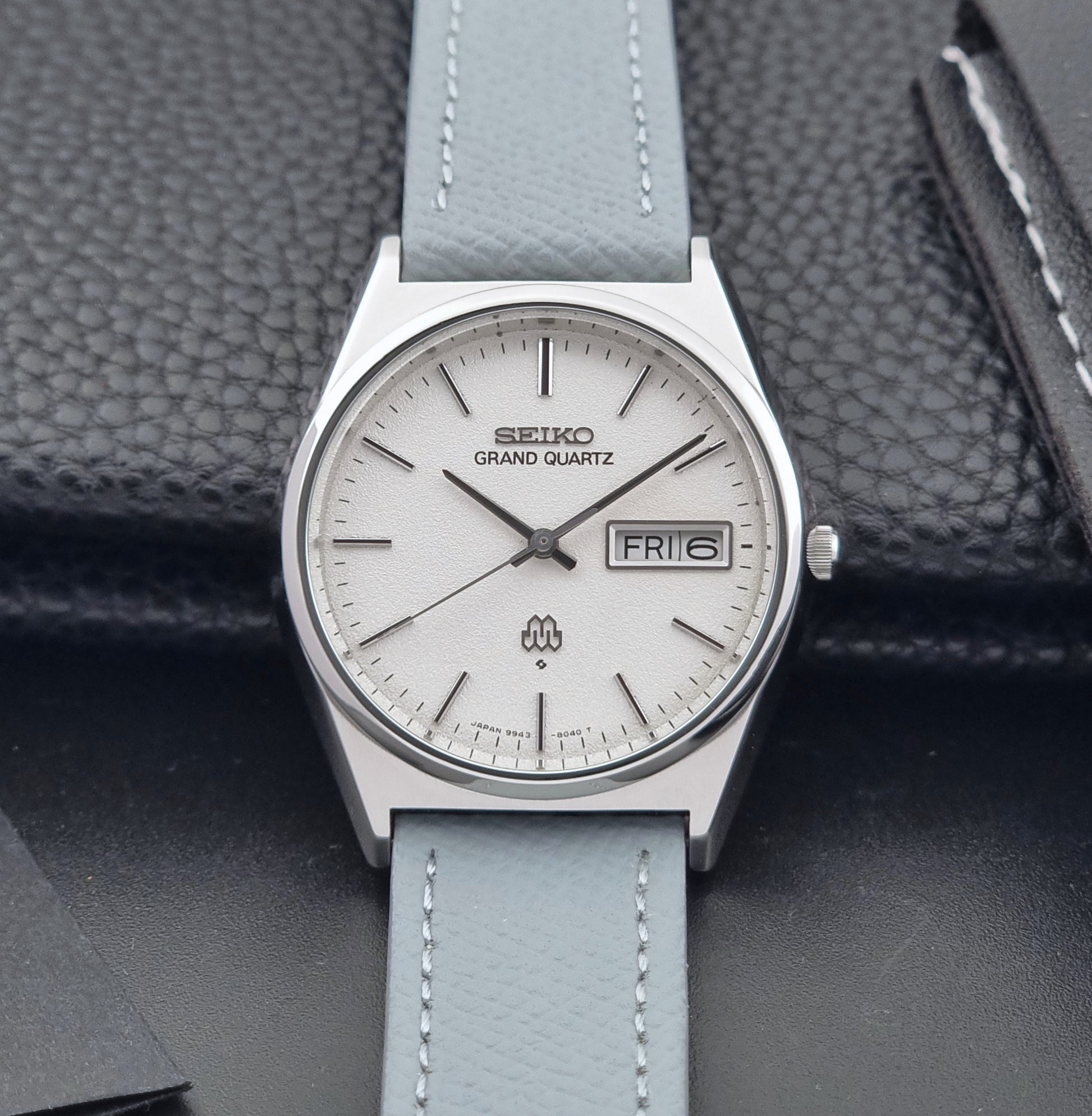 Vintage Seiko Grand Quartz watch 9943-8030 with a leather strap on a dark gray background front view