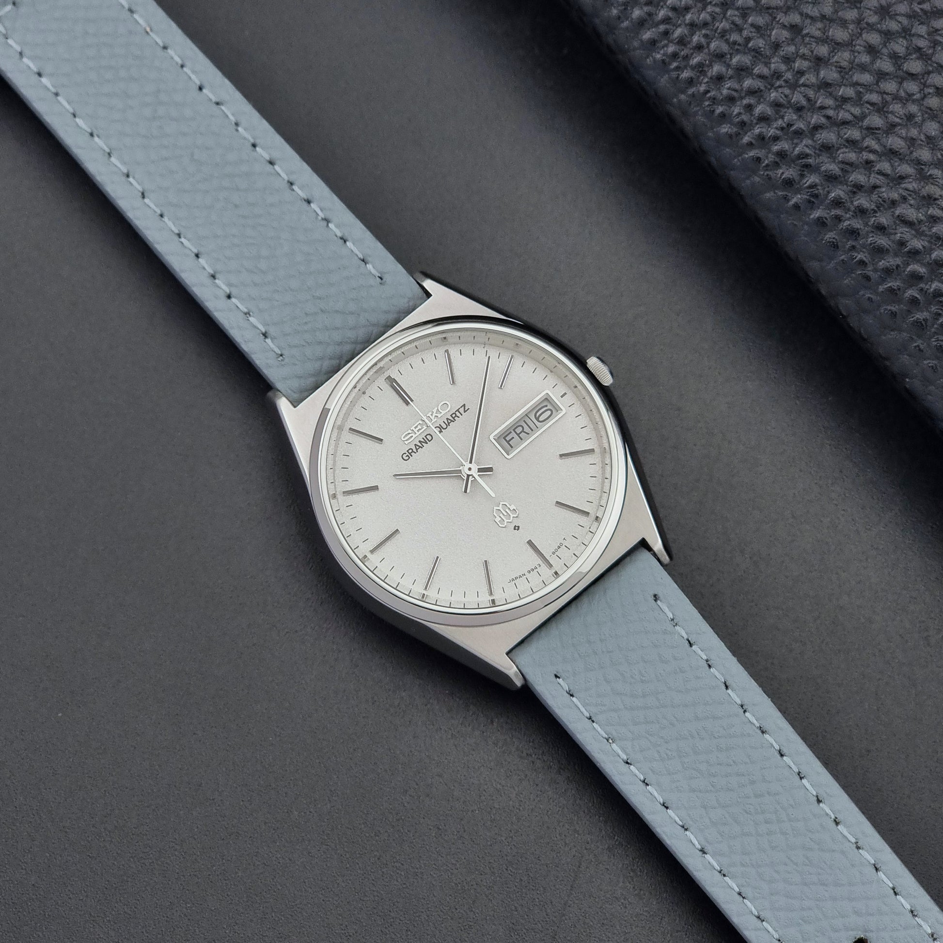 Vintage Seiko Grand Quartz watch 9943-8030 with a leather strap on a dark gray background dial