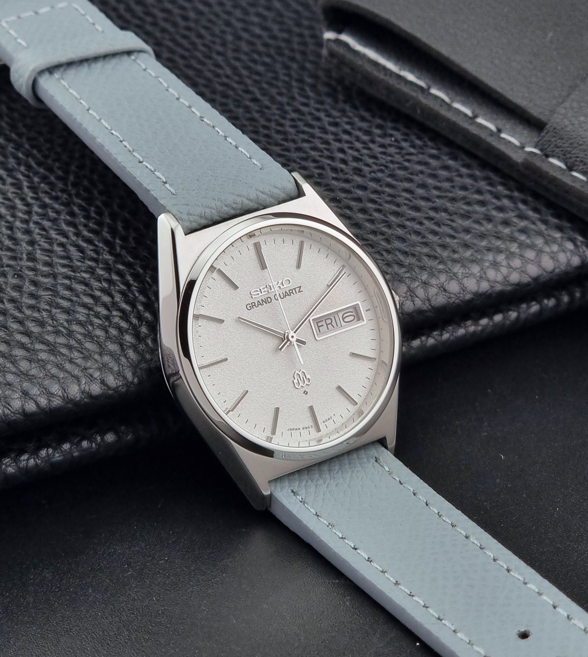 Vintage Seiko Grand Quartz watch 9943-8030 with a leather strap on a dark gray background side view
