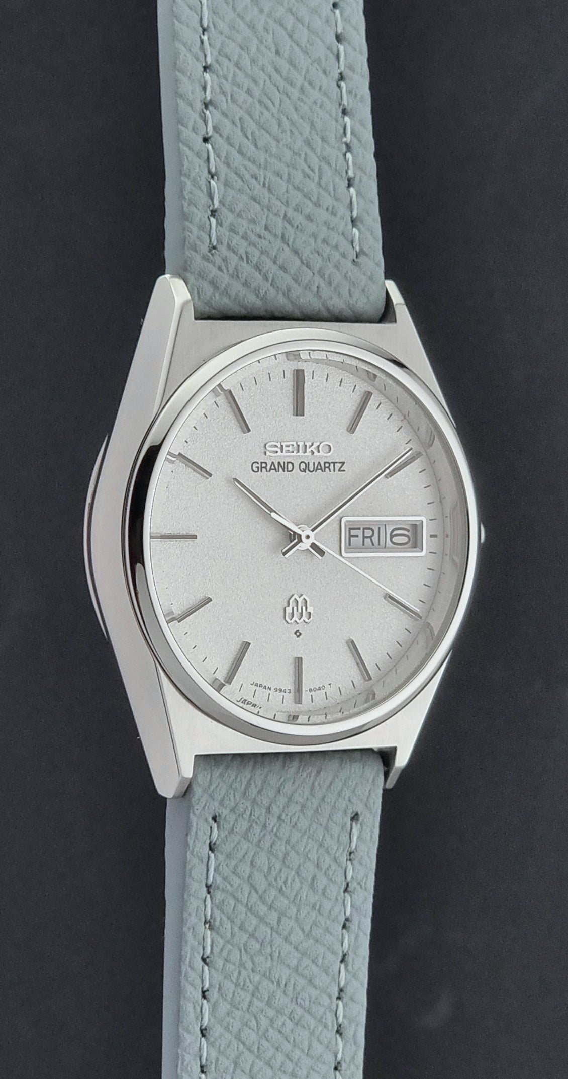 Vintage Seiko Grand Quartz watch 9943-8030 with a leather strap on a dark gray background side profile view