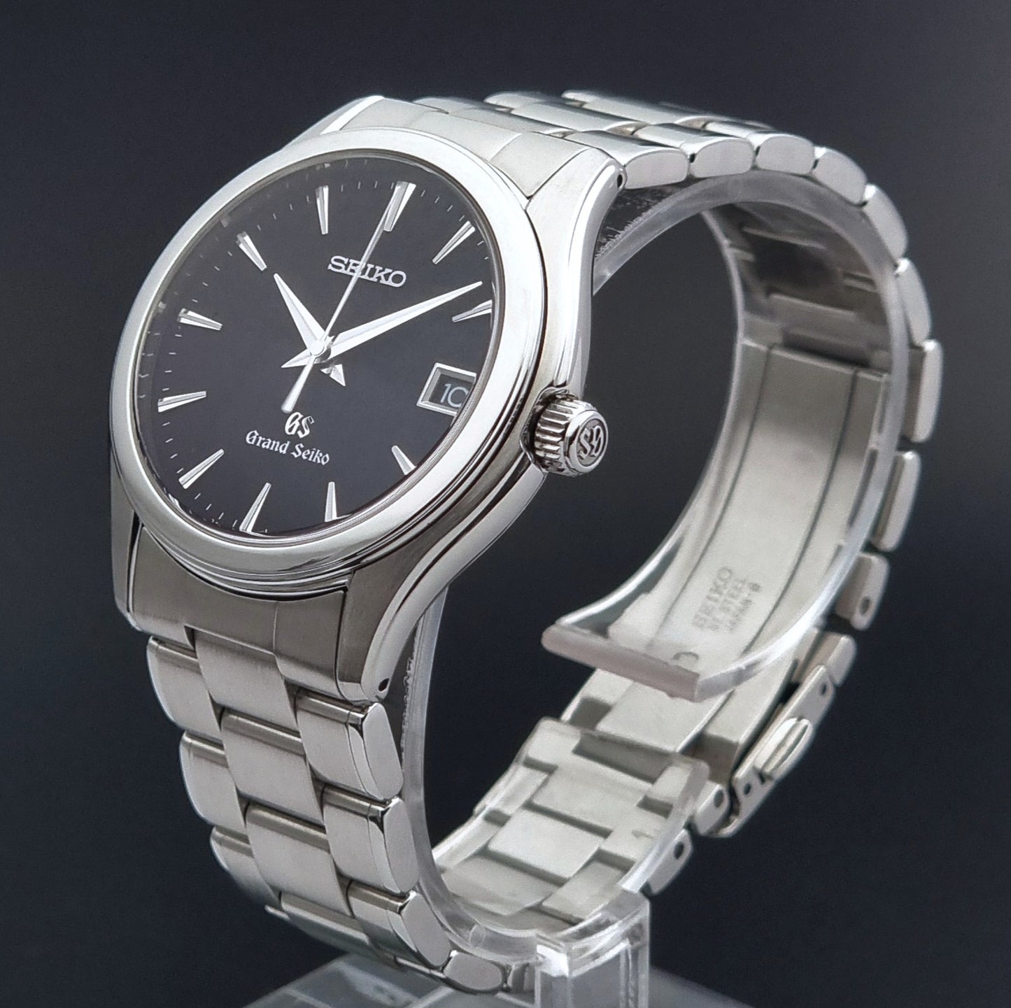 Grand Seiko quartz SBGX041 watch with black dial on a display holder showing the GS signed crown on a dark background