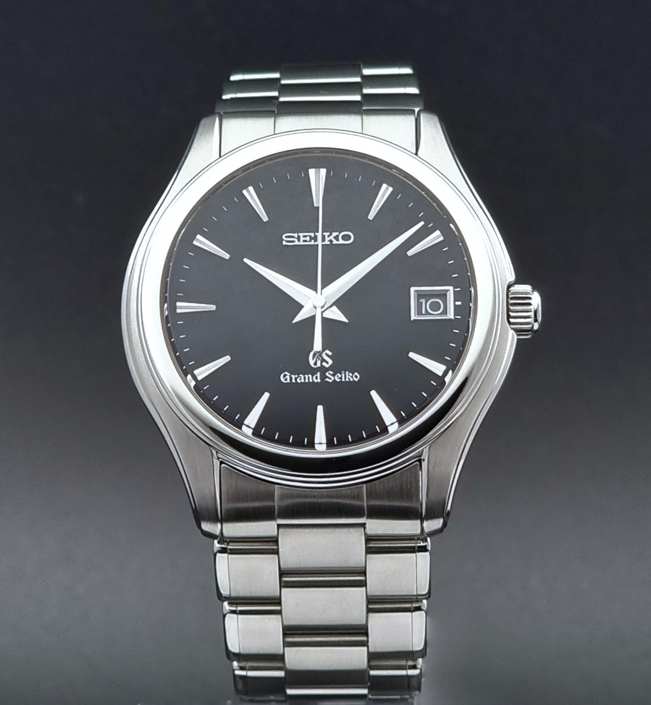 Grand Seiko quartz SBGX041 watch with black dial and silver metal strap on a dark background
