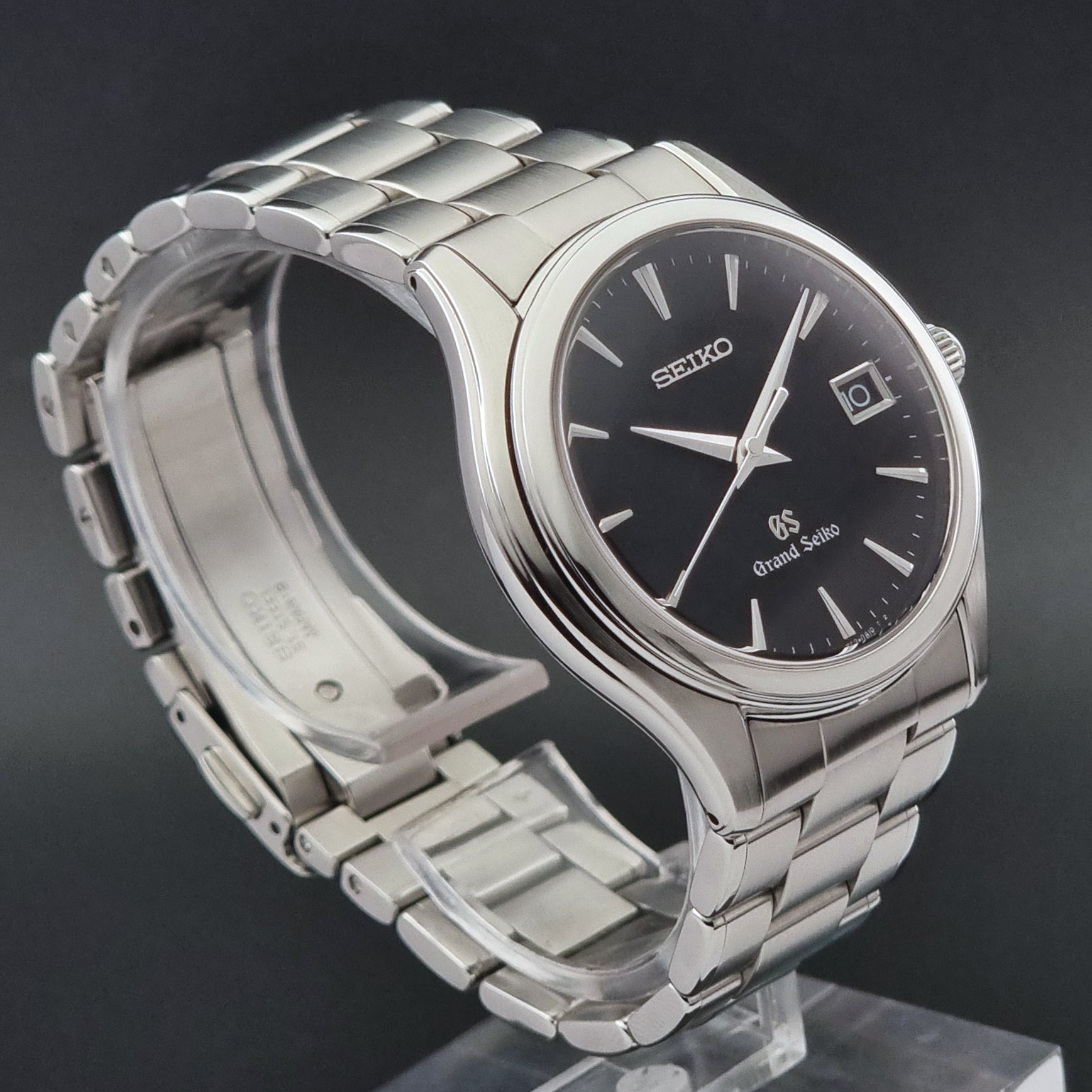 Grand Seiko quartz SBGX041 watch with black dial on a display holder showing the side of the watch on a dark background
