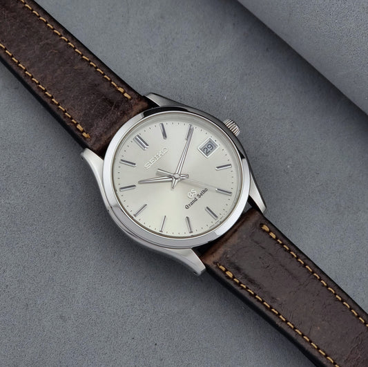 Grand Seiko SBGV001 quartz watch 9F82-0A10 with brown leather strap on a gray background dial