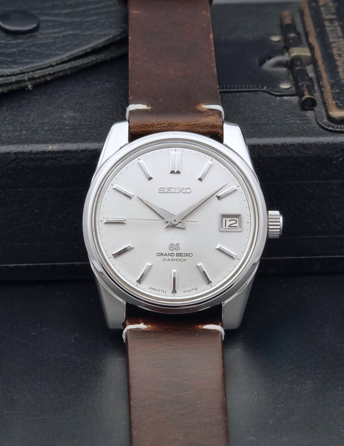Vintage Grand Seiko 5722-9991 wristwatch with a silver dial, silver case, and a brown leather strap, shown on a dark gray background dial view