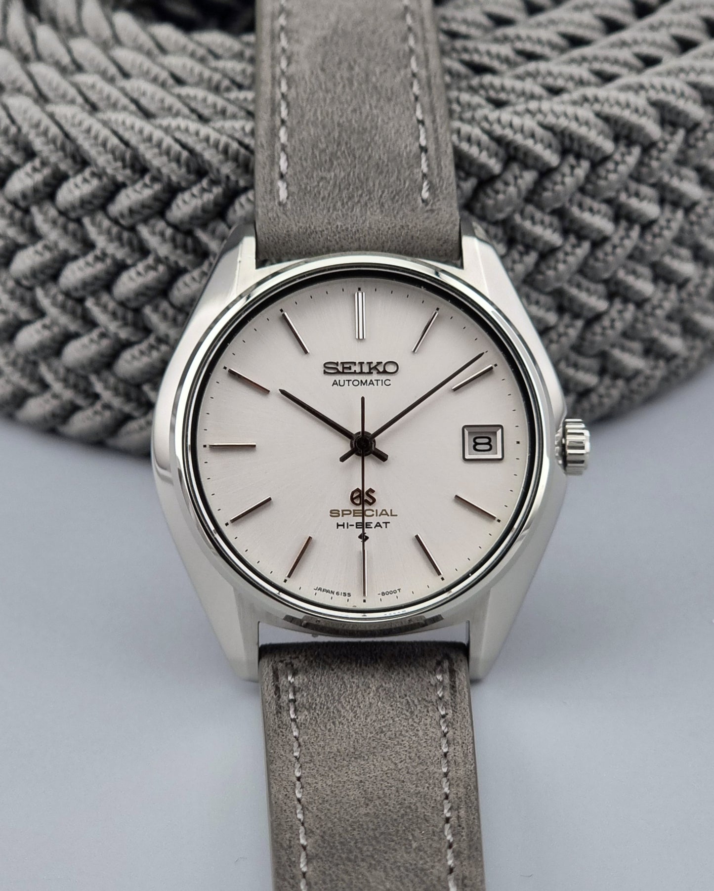 Grand Seiko watch with gray strap on a textured gray background