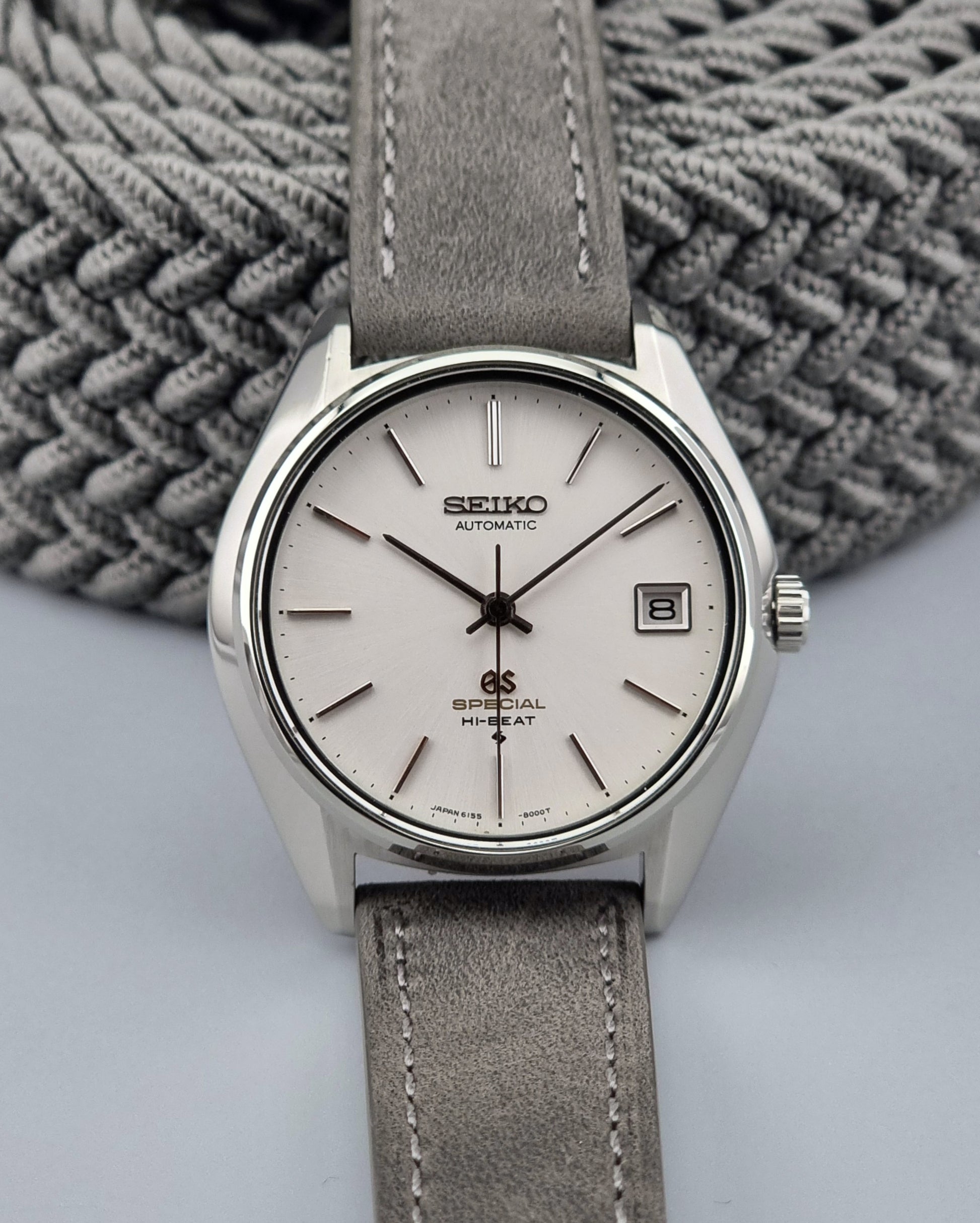 Grand Seiko watch with gray strap on a textured gray background