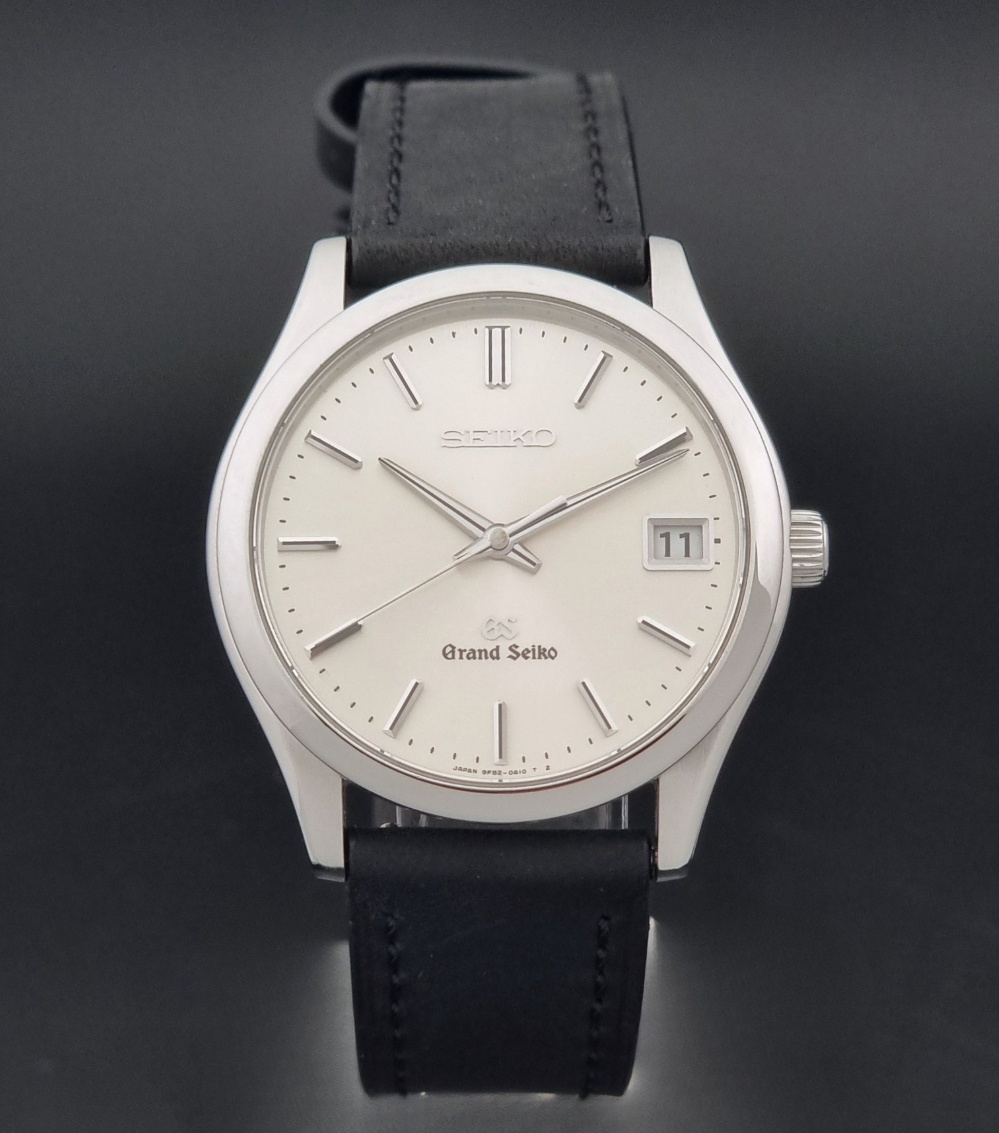 Grand Seiko SBGV001 quartz watch 9F82-0A10 with a silver-toned case,  and black leather strap, on a dark background close dial view