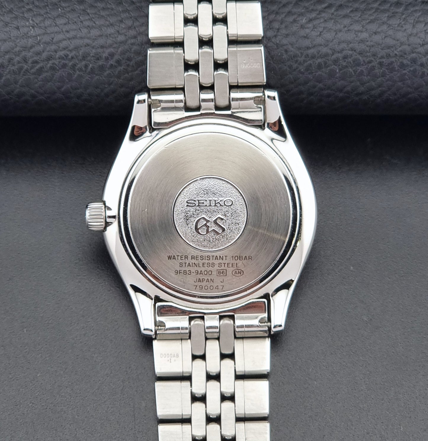 Vintage Grand Seiko watch SBGT001 9F83-9A00 with a white dial on a dark background caseback view