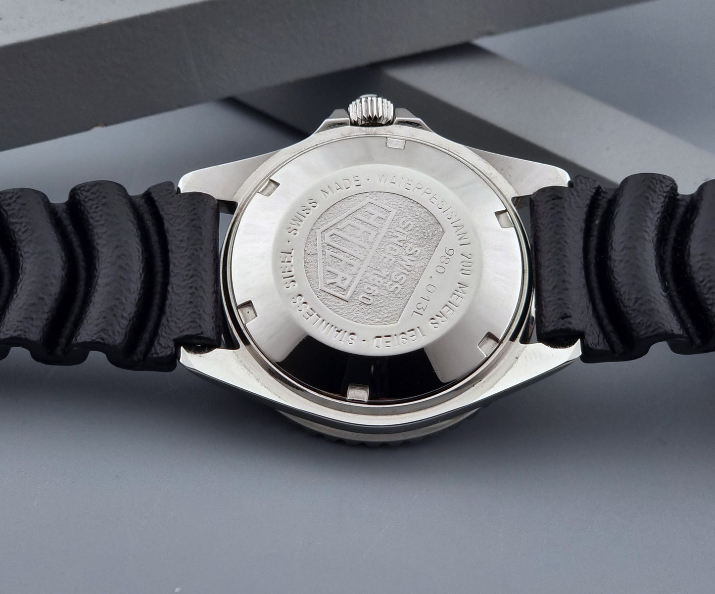 Vintage Heuer watch Professional Quartz 1000 980.013L with black strap and black dial on a light gray background case back view