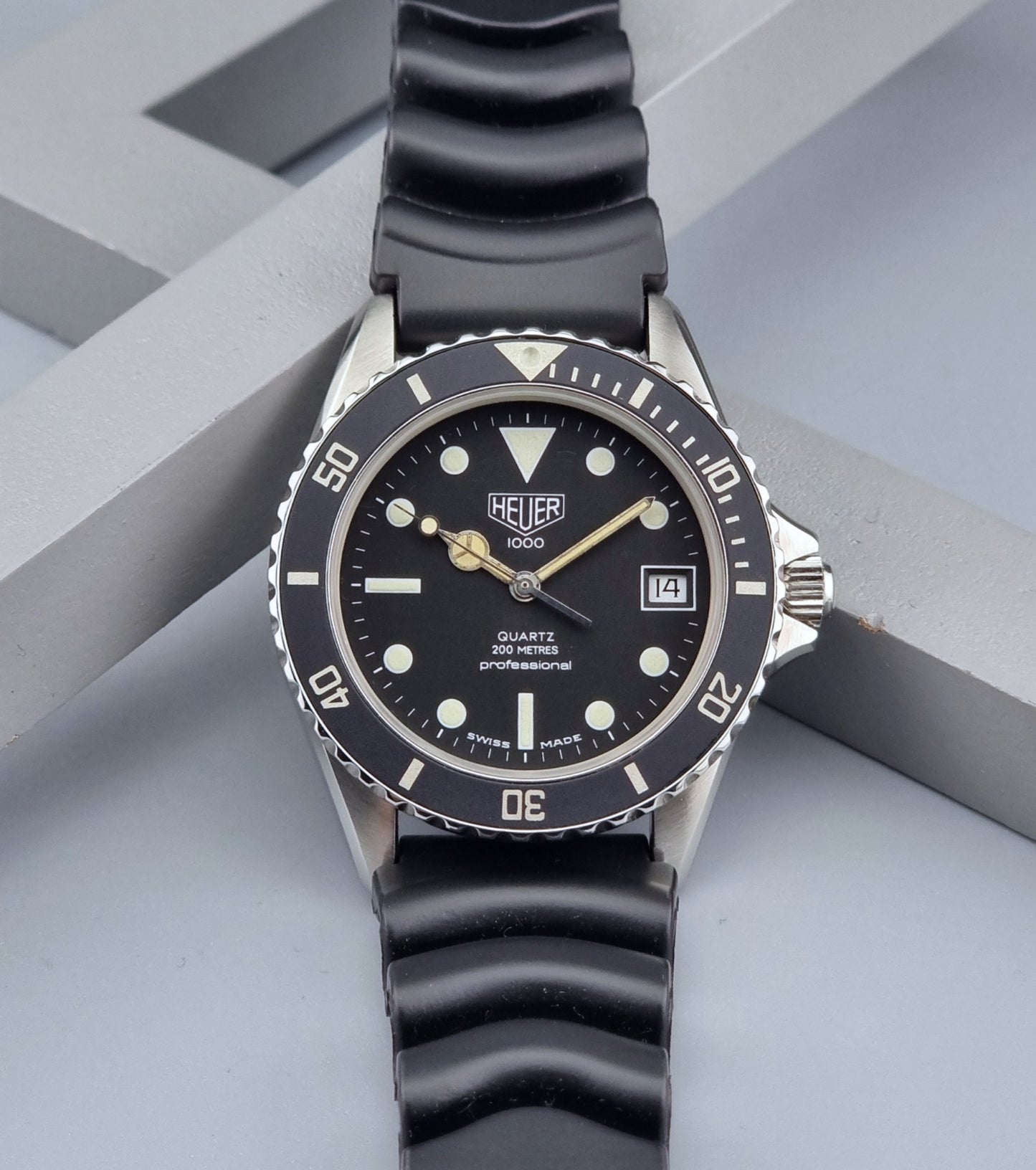 Vintage Heuer watch Professional Quartz 1000 980.013L with black strap and black dial on a light gray background dial view