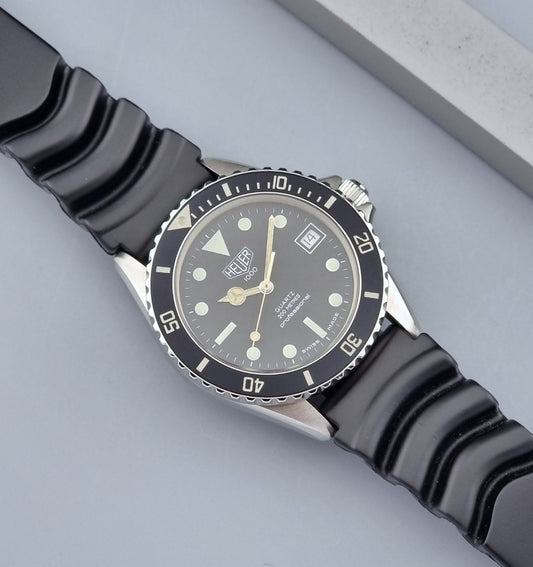 Vintage Heuer watch Professional Quartz 1000 980.013L with black strap and black dial on a light gray background dial