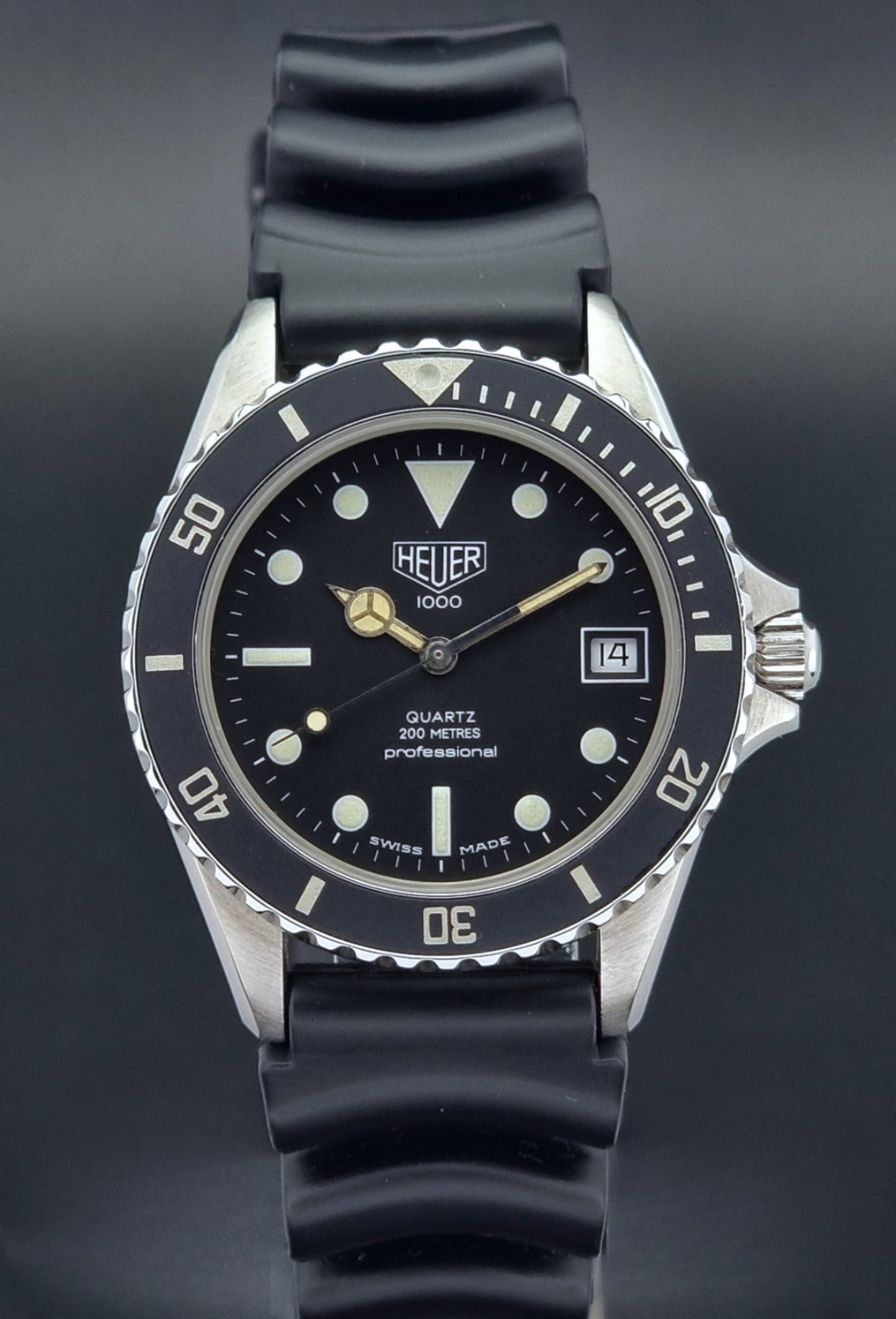 Vintage Heuer watch Professional Quartz 1000 980.013L with black strap and black dial on a light gray background close dial view