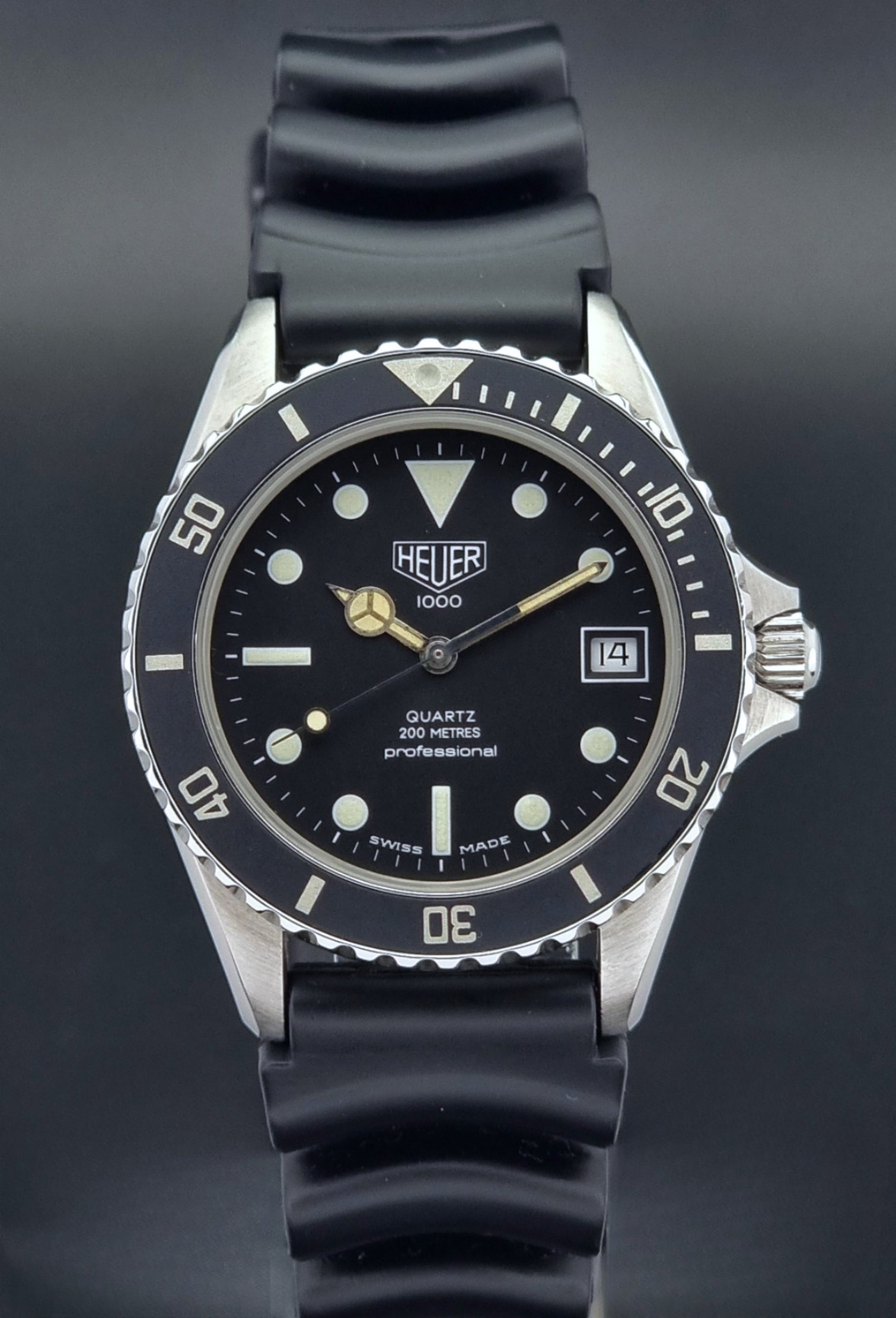 Vintage Heuer watch Professional Quartz 1000 980.013L with black strap and black dial on a light gray background close dial view