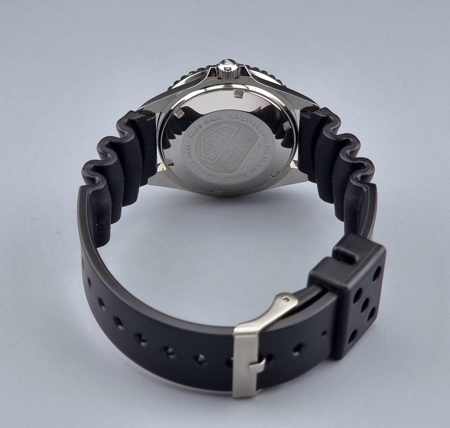 Vintage Heuer watch Professional Quartz 1000 980.013L with black strap and black dial on a light gray background strap view