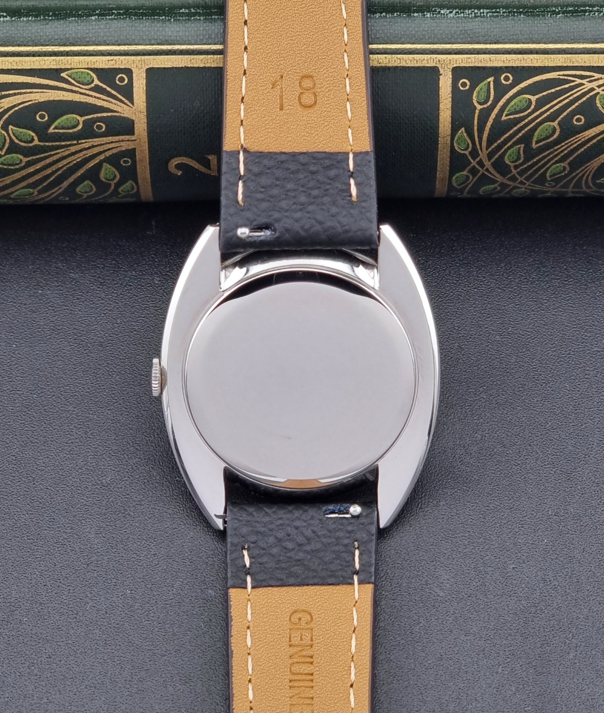 Vintage IWC R1419 Wristwatch with a black strap and silver dial on a dark background case back view