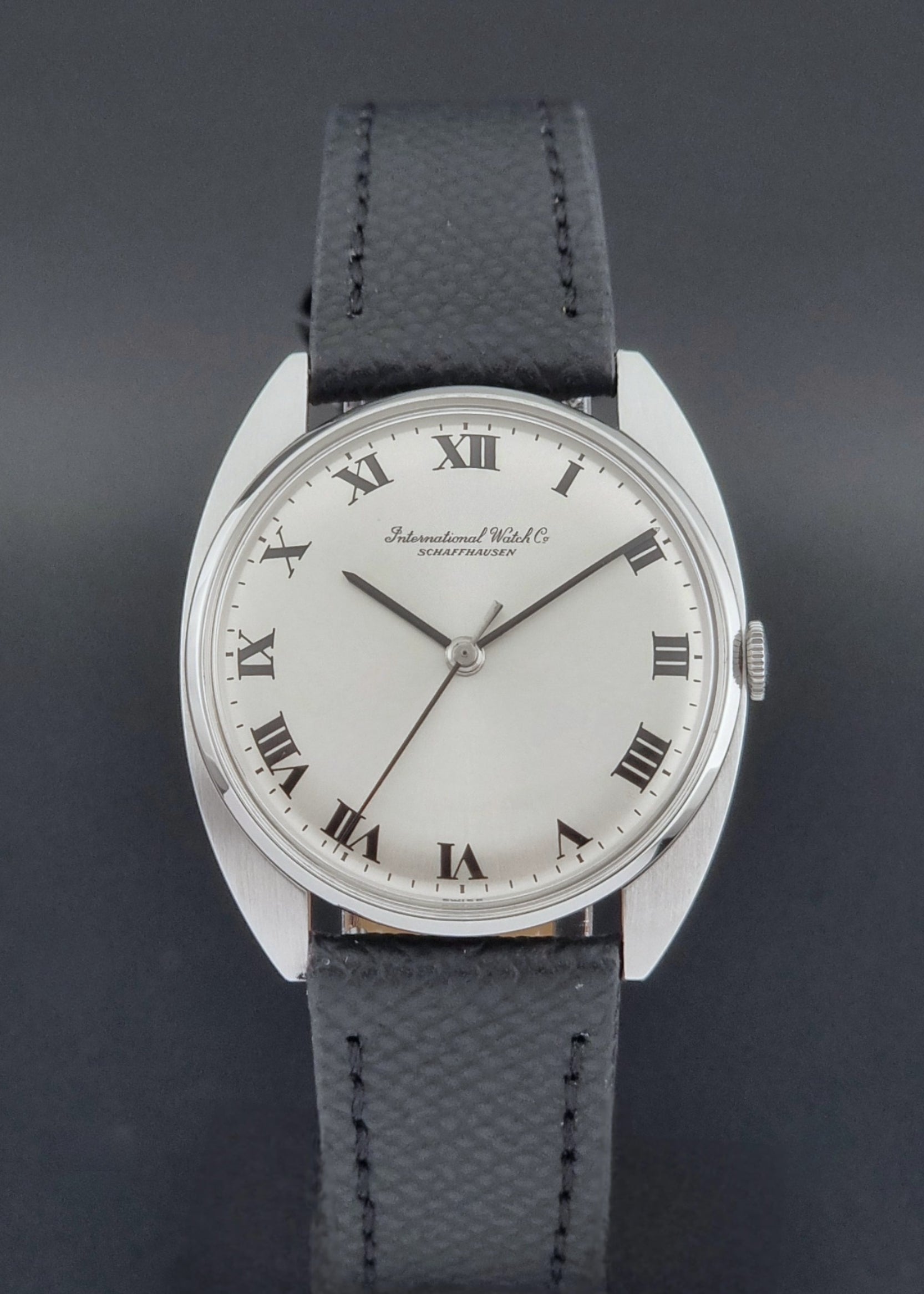 Vintage IWC R1419 Wristwatch with a black strap and silver dial on a dark background close dal view