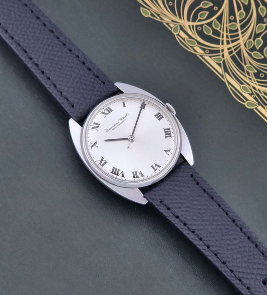 Vintage IWC R1419 Wristwatch with a black strap and silver dial on a dark background dial