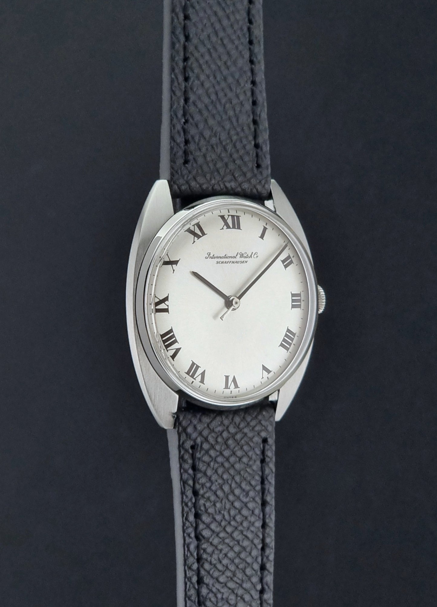 Vintage IWC R1419 Wristwatch with a black strap and silver dial on a dark background side profile view