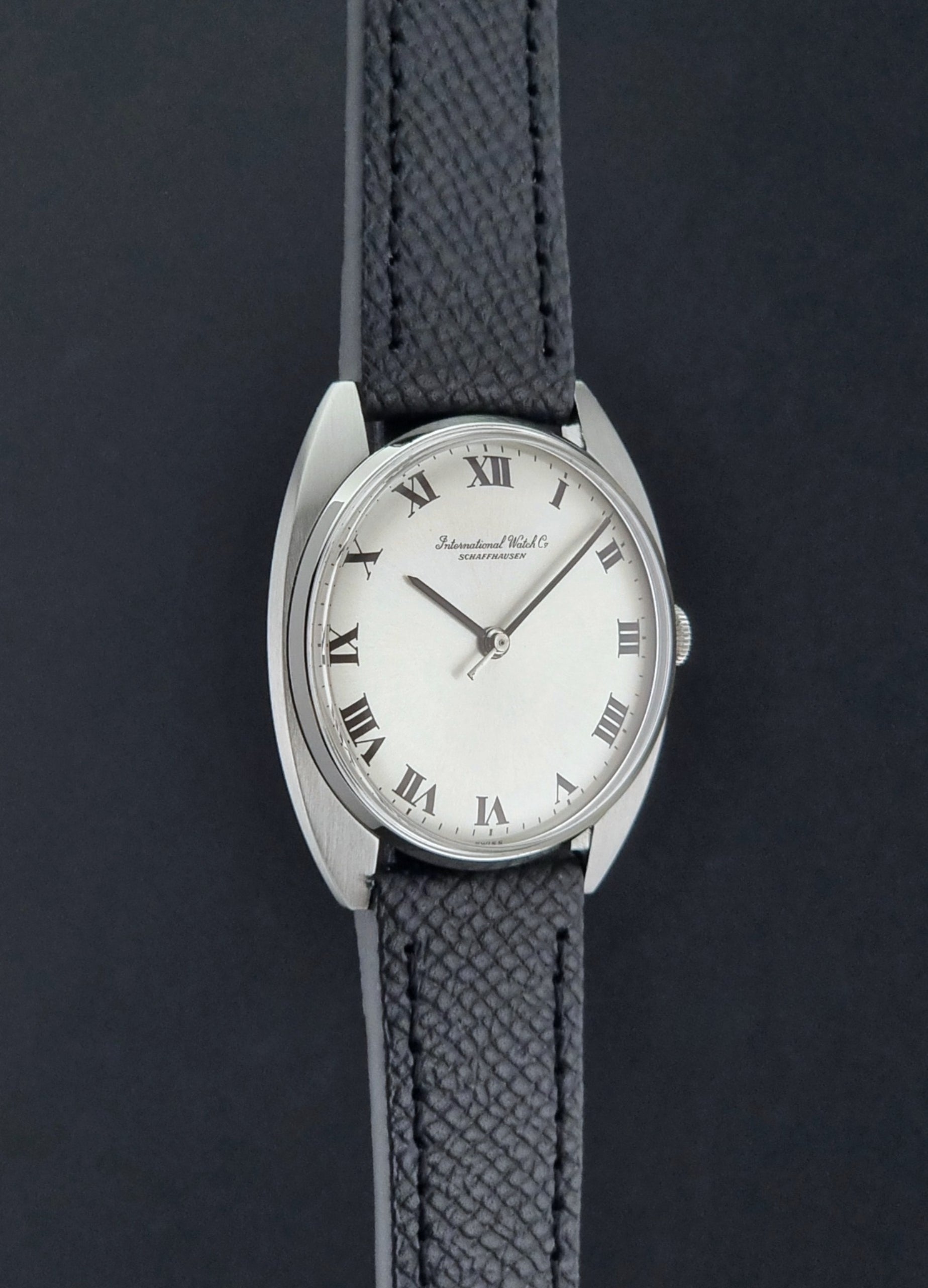 Vintage IWC R1419 Wristwatch with a black strap and silver dial on a dark background side profile view