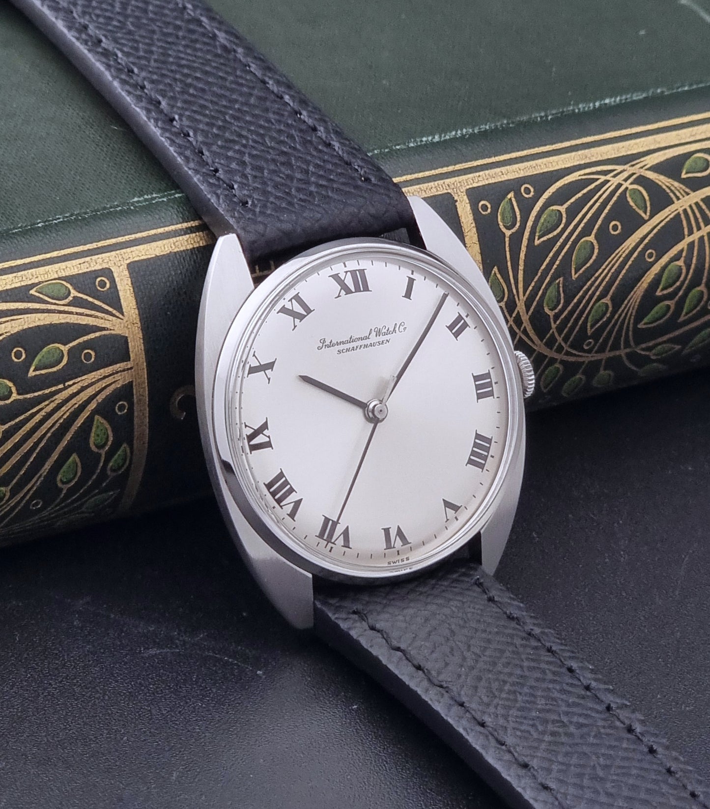 Vintage IWC R1419 Wristwatch with a black strap and silver dial on a dark background side view