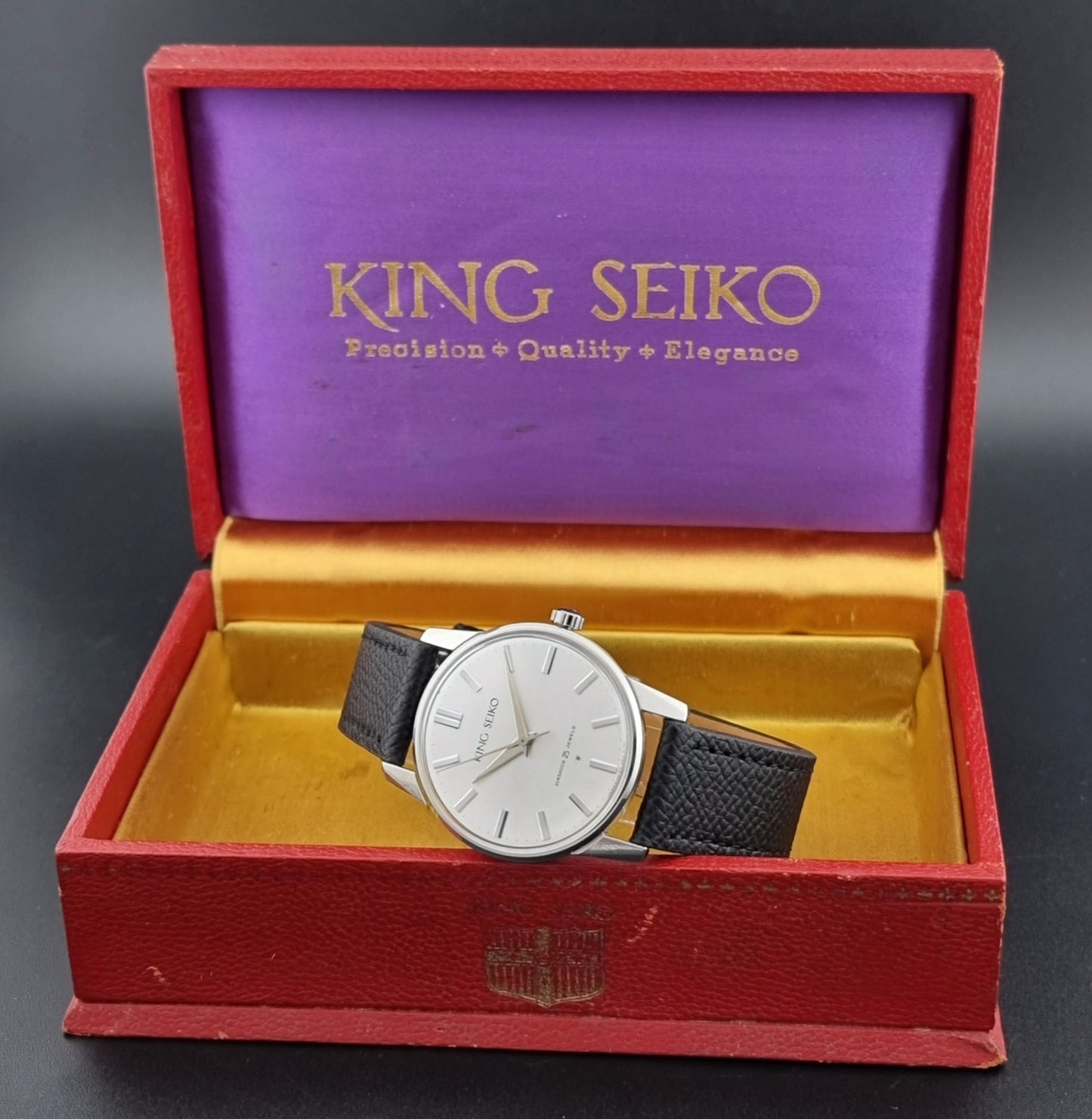 Vintage King Seiko Wristwatch 15034 with a black leather strap on a gray surface box view