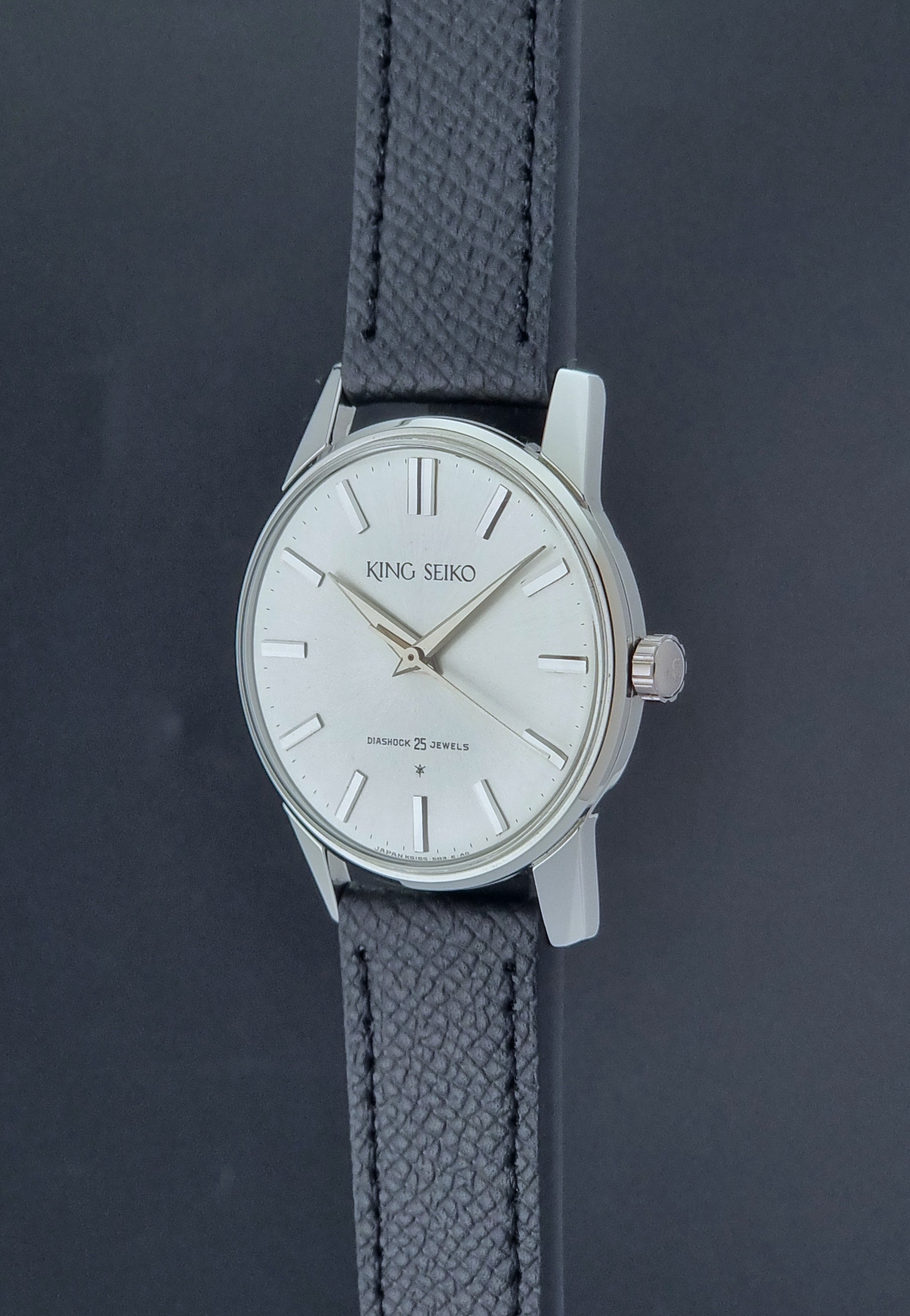Vintage King Seiko Wristwatch 15034 with a black leather strap on a gray surface crown profile view