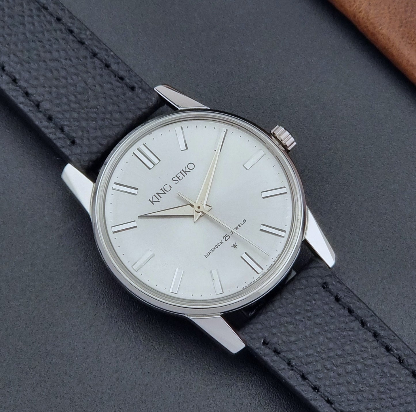 Vintage King Seiko Wristwatch 15034 with a black leather strap on a gray surface close up dial view