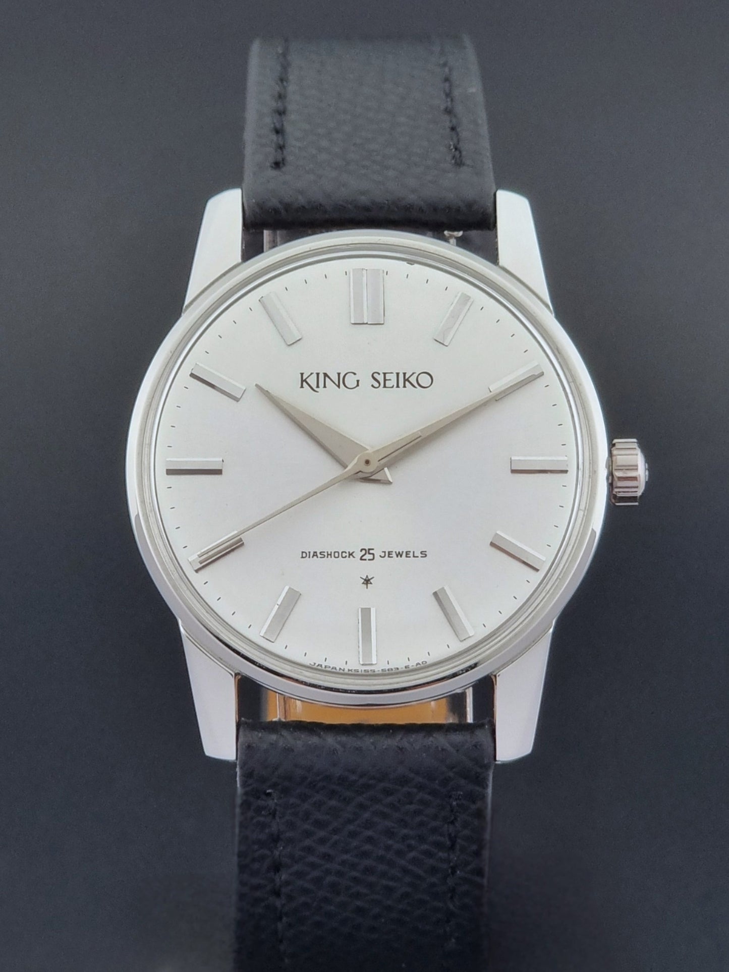 Vintage King Seiko Wristwatch 15034 with a black leather strap on a gray surface close dial view