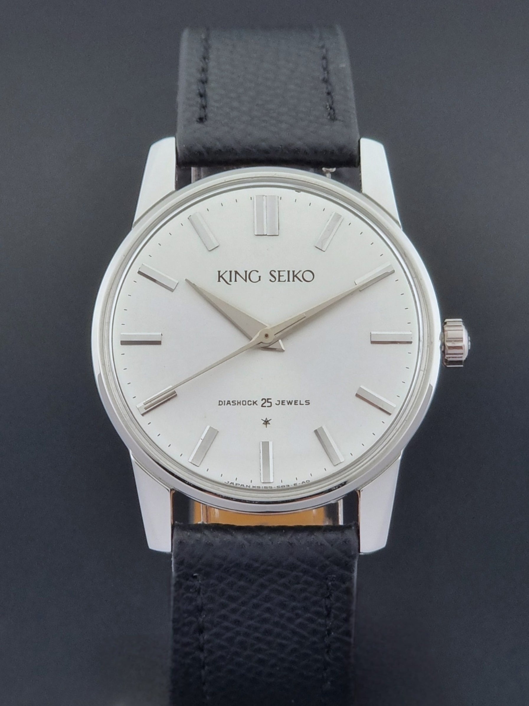 Vintage King Seiko Wristwatch 15034 with a black leather strap on a gray surface close dial view