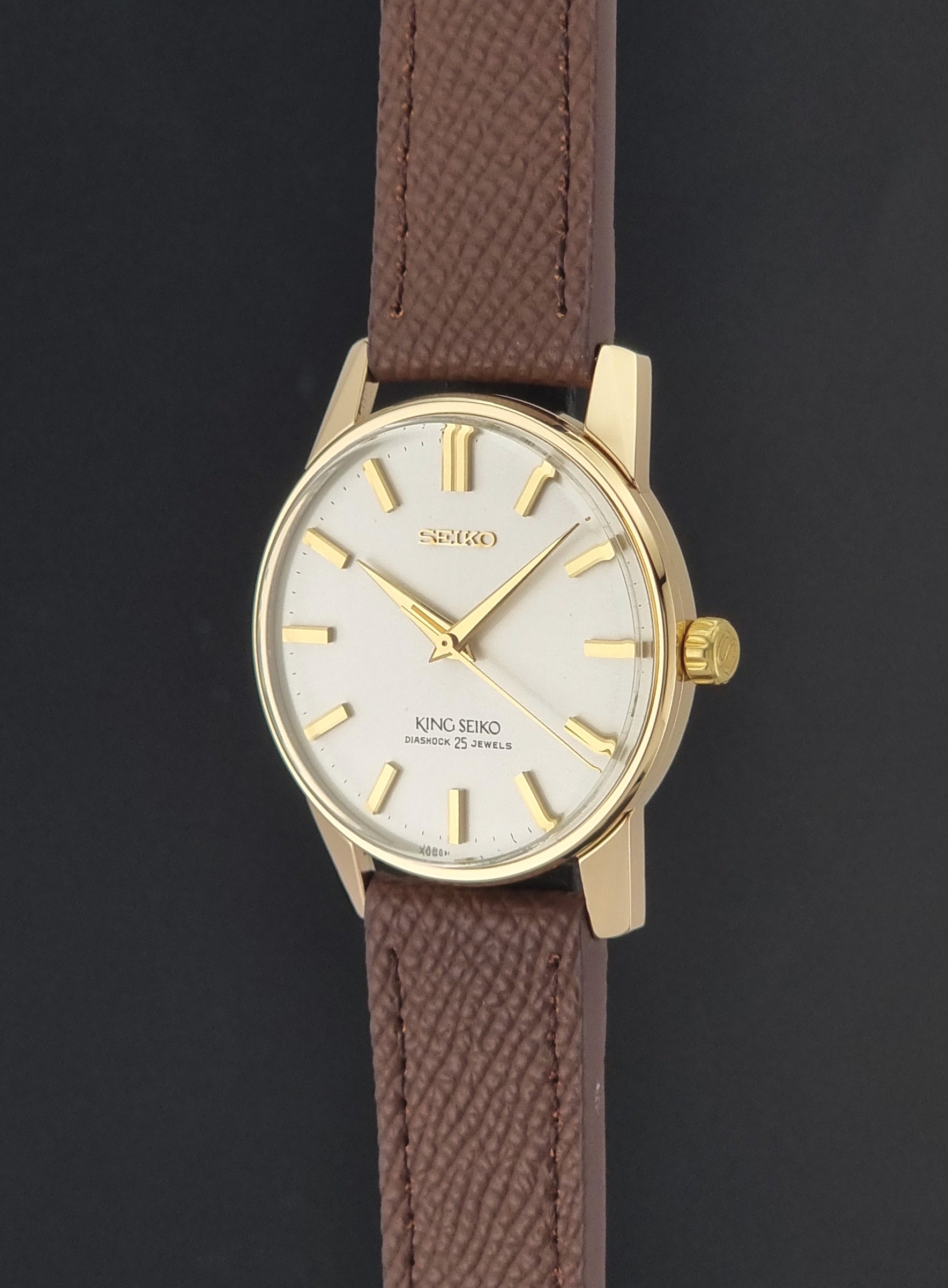 Vintage King Seiko Wristwatch 44-2000 with a gold filled case and brown leather strap on a dark background crown profile view