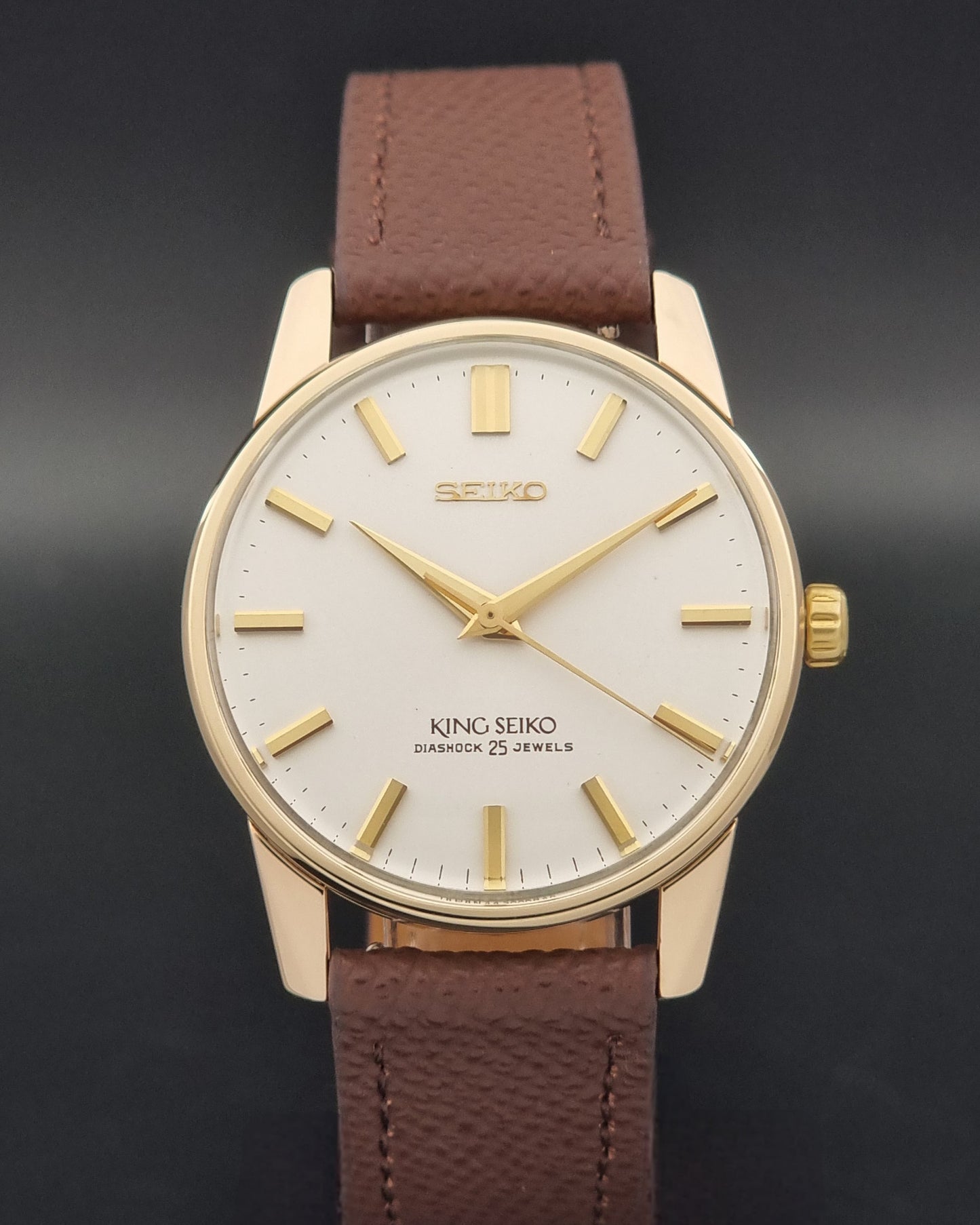 Vintage King Seiko Wristwatch 44-2000 with a gold filled case and brown leather strap on a dark background close dial view