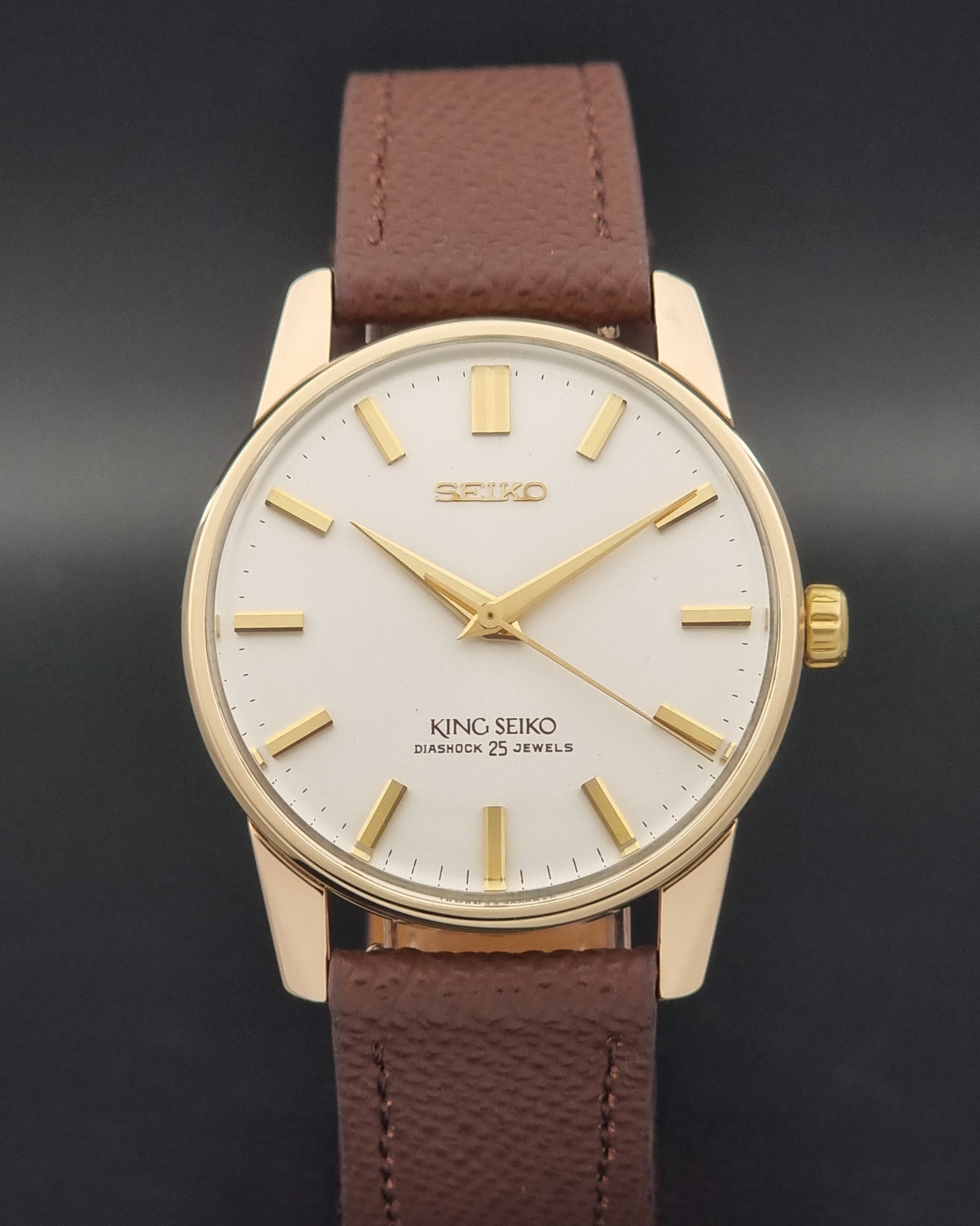 Vintage King Seiko Wristwatch 44-2000 with a gold filled case and brown leather strap on a dark background close dial view