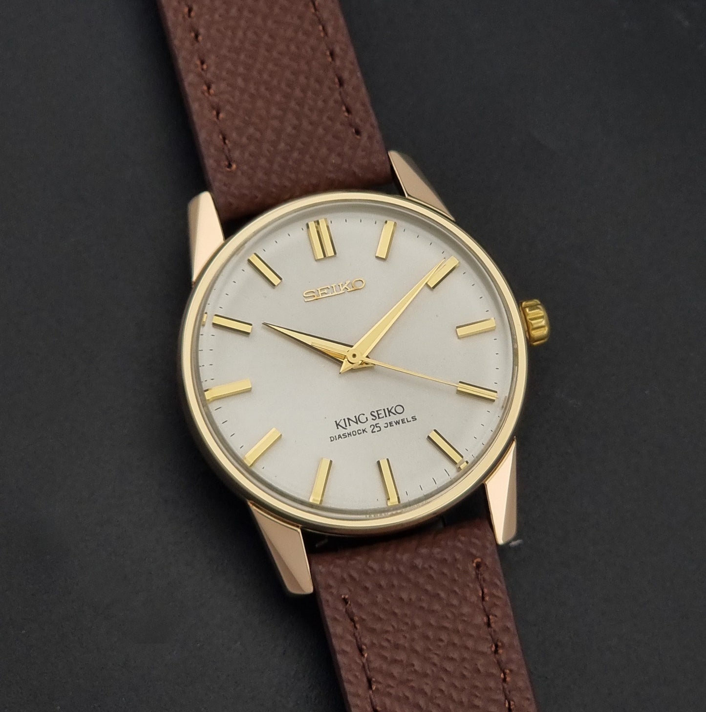 Vintage King Seiko Wristwatch 44-2000 with a gold filled case and brown leather strap on a dark background front view