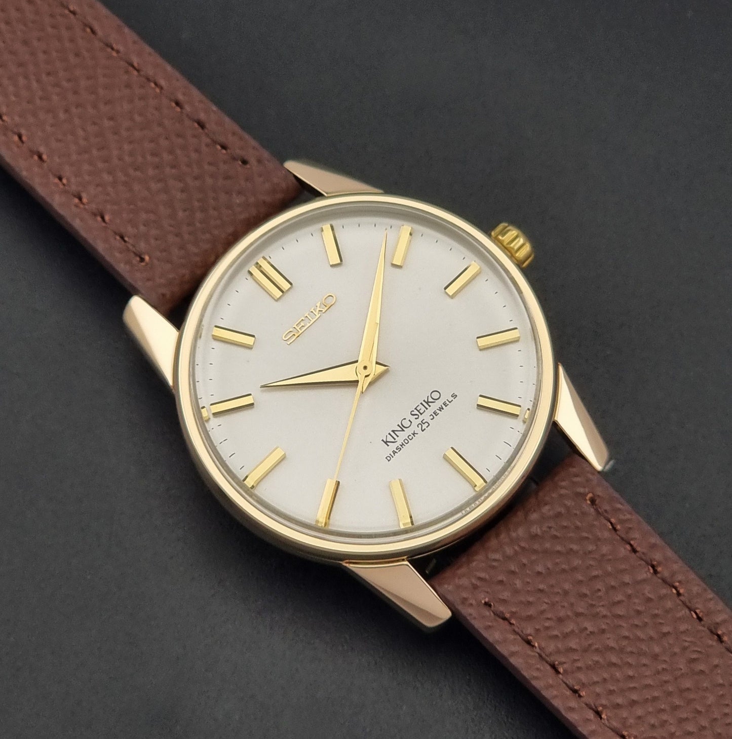 Vintage King Seiko Wristwatch 44-2000 with a gold filled case and brown leather strap on a dark background close up dial view