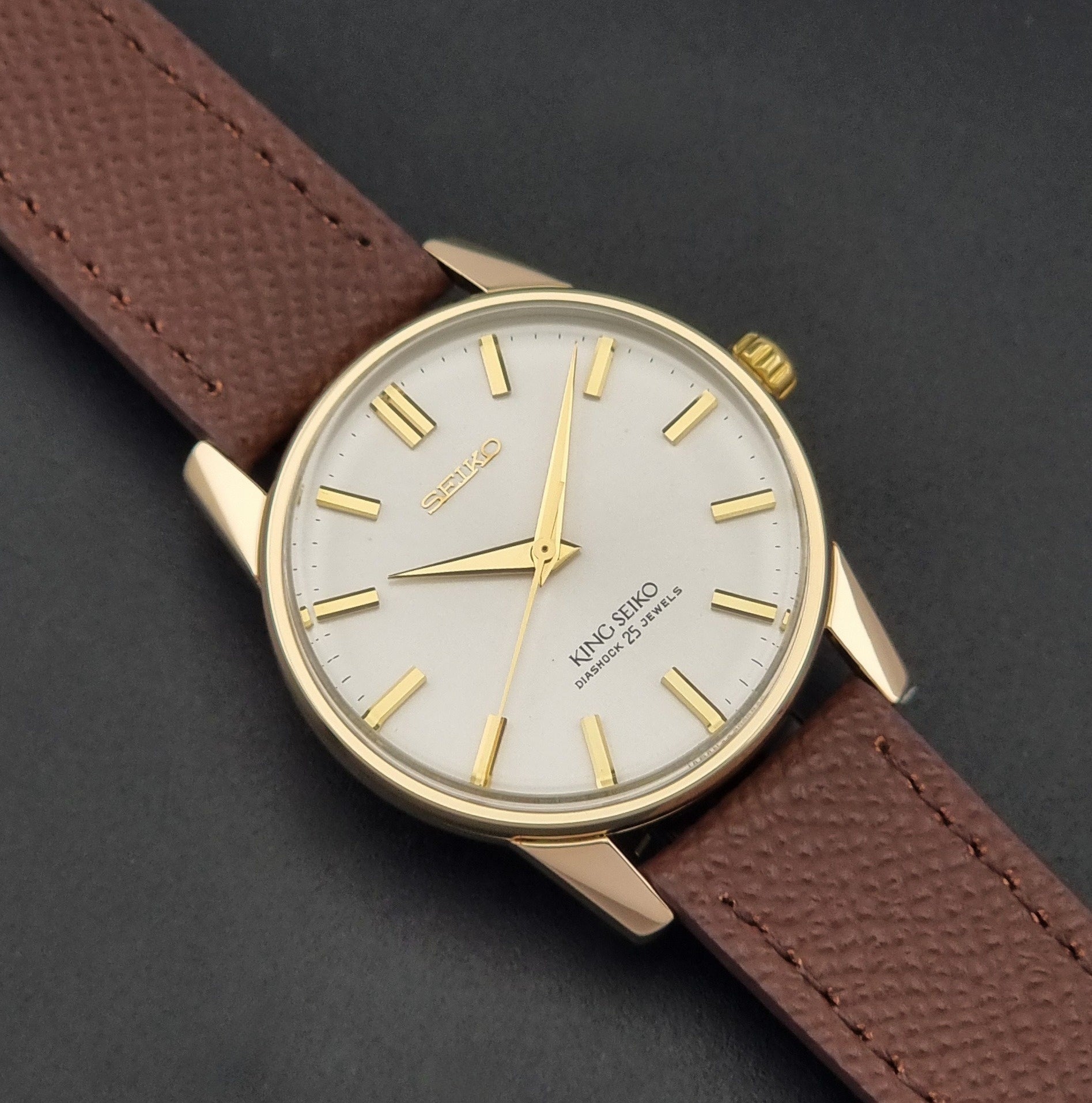 Vintage King Seiko Wristwatch 44-2000 with a gold filled case and brown leather strap on a dark background close up dial view