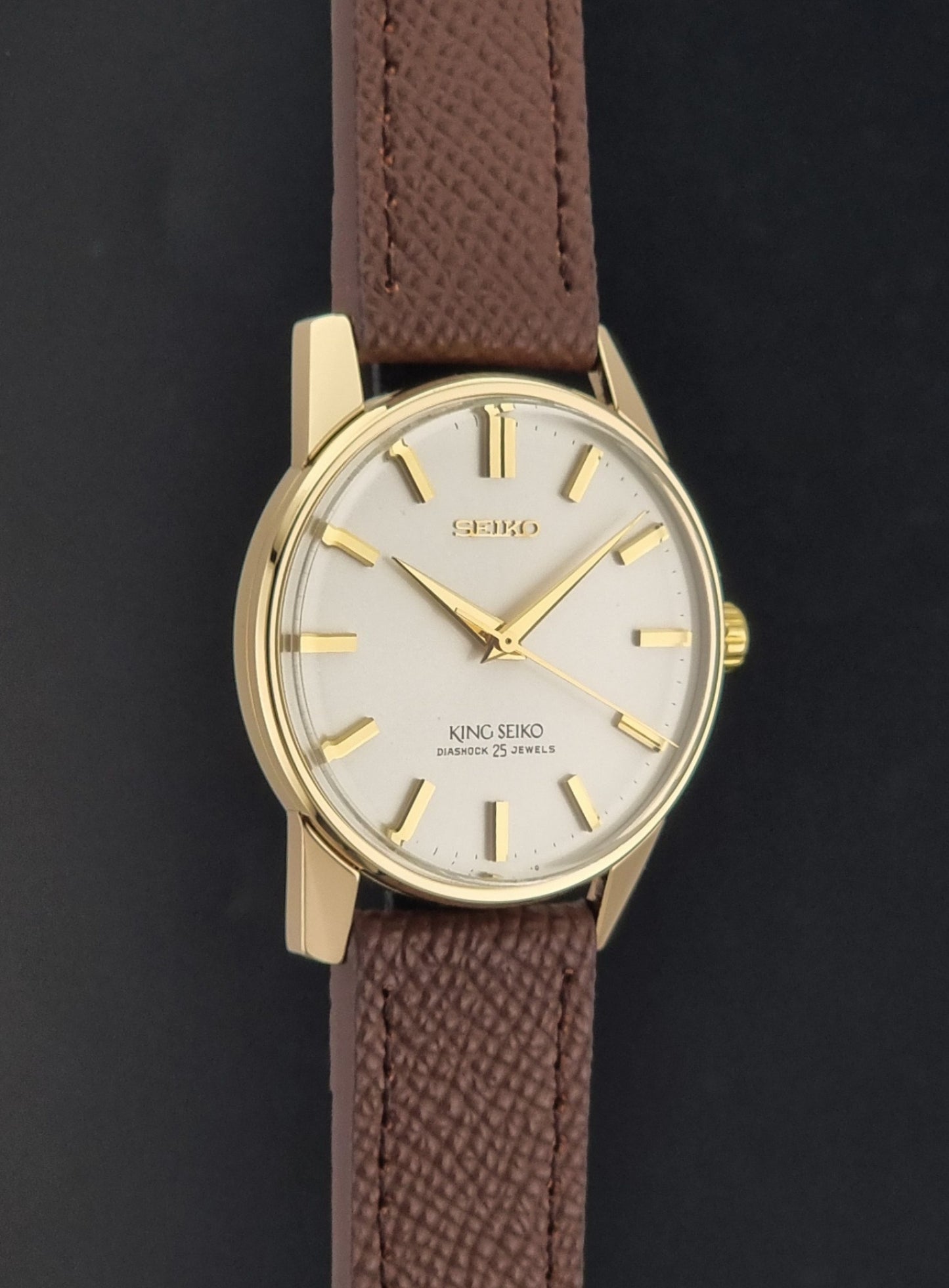 Vintage King Seiko Wristwatch 44-2000 with a gold filled case and brown leather strap on a dark background side profile view