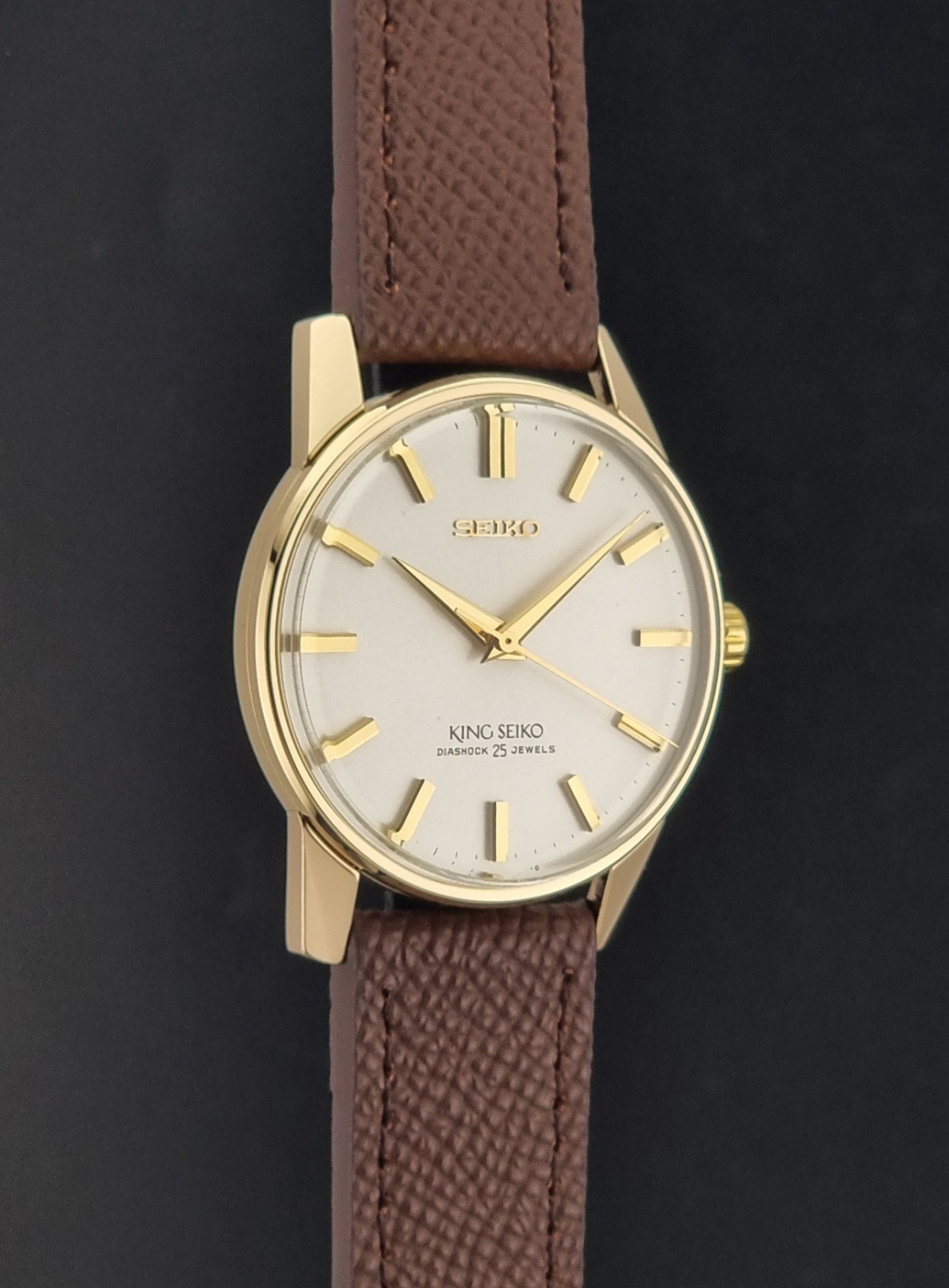 Vintage King Seiko Wristwatch 44-2000 with a gold filled case and brown leather strap on a dark background side profile view