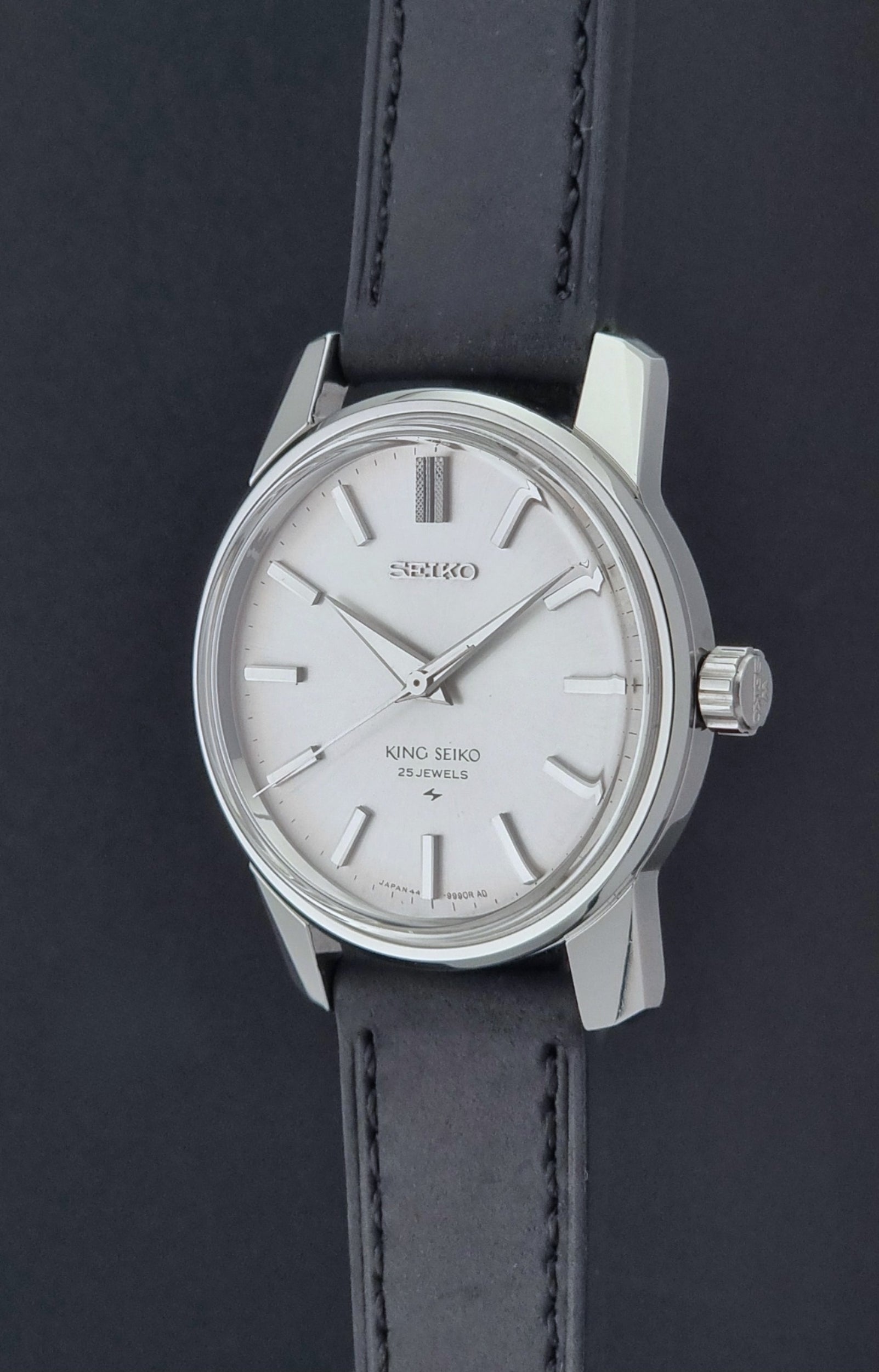 Vintage King Seiko 44-9990 wristwatch with black leather strap and silver case on a dark background crown profile view