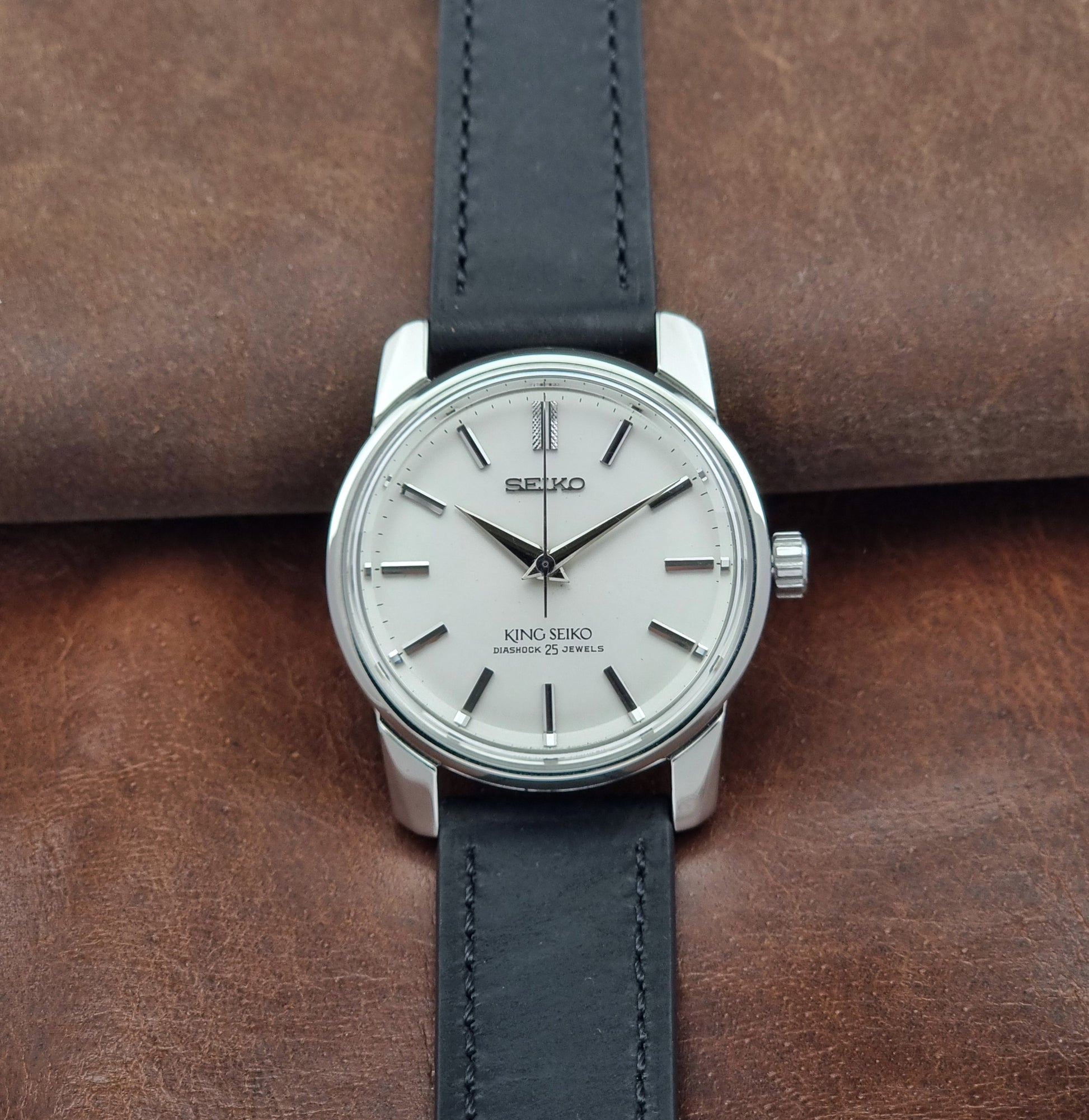 Vintage King Seiko 44-999 Watch with black leather strap on a brown leather background