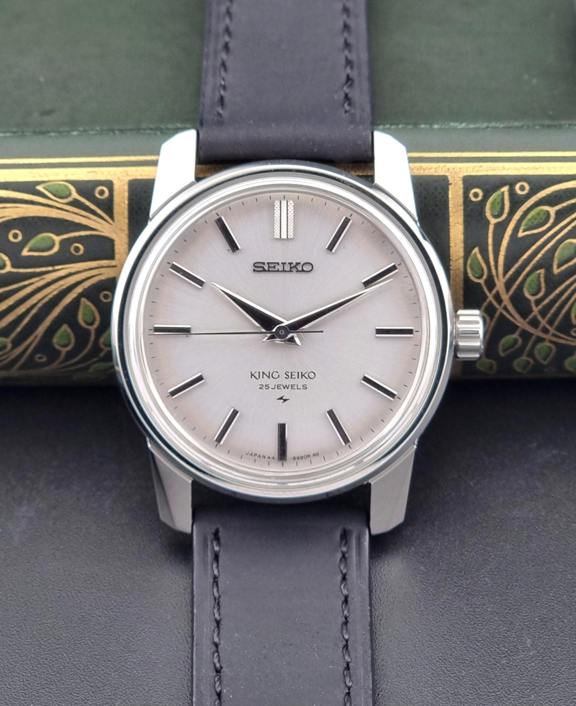 Vintage King Seiko 44-9990 wristwatch with black leather strap and silver case on a dark background front view