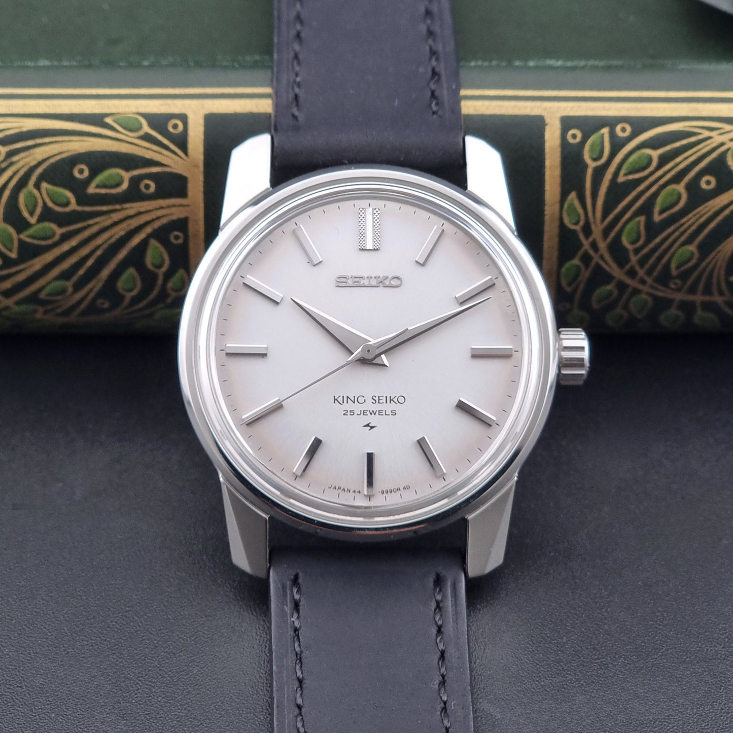 Vintage King Seiko 44-9990 wristwatch with black leather strap and silver case on a dark background dial view