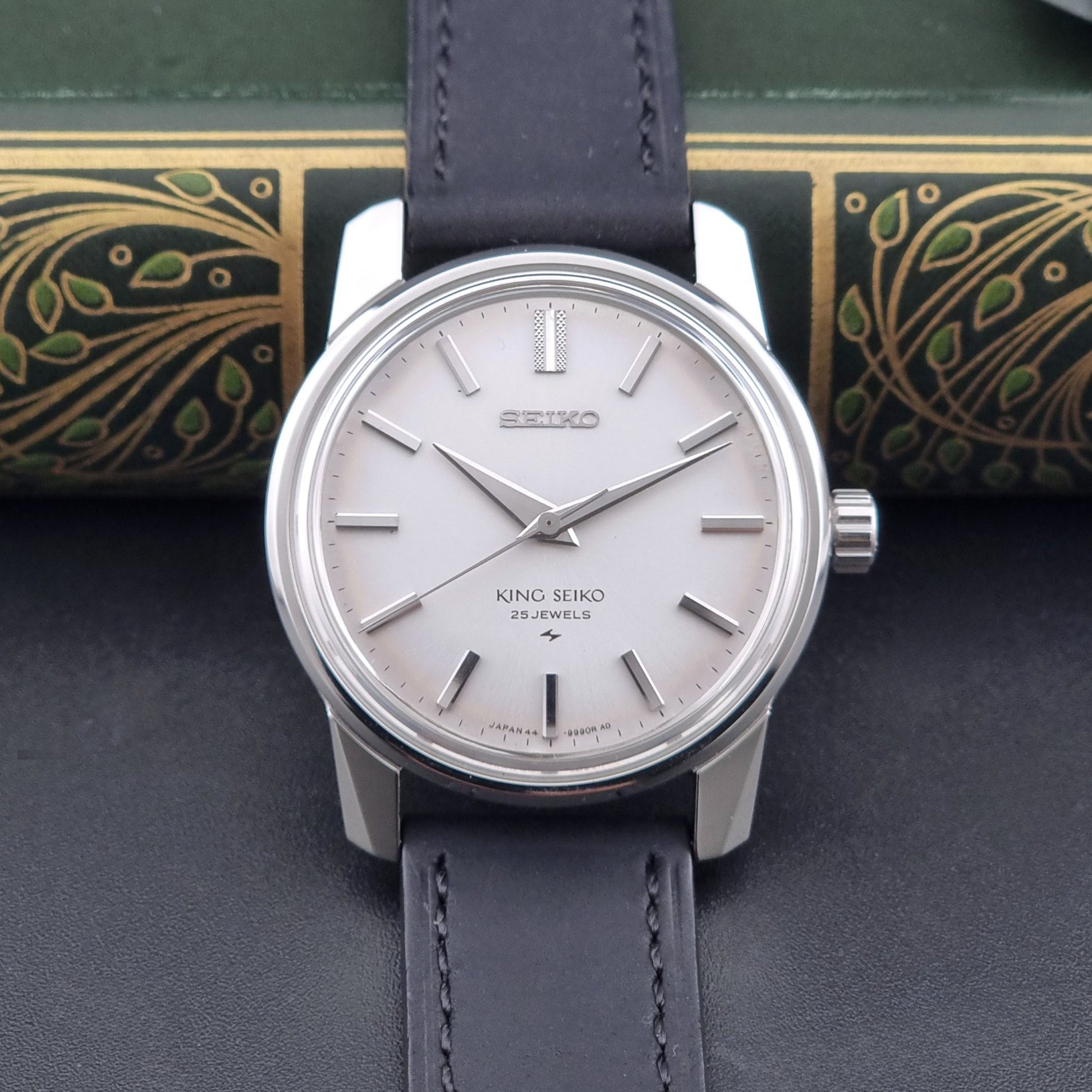 Vintage King Seiko 44-9990 wristwatch with black leather strap and silver case on a dark background dial view