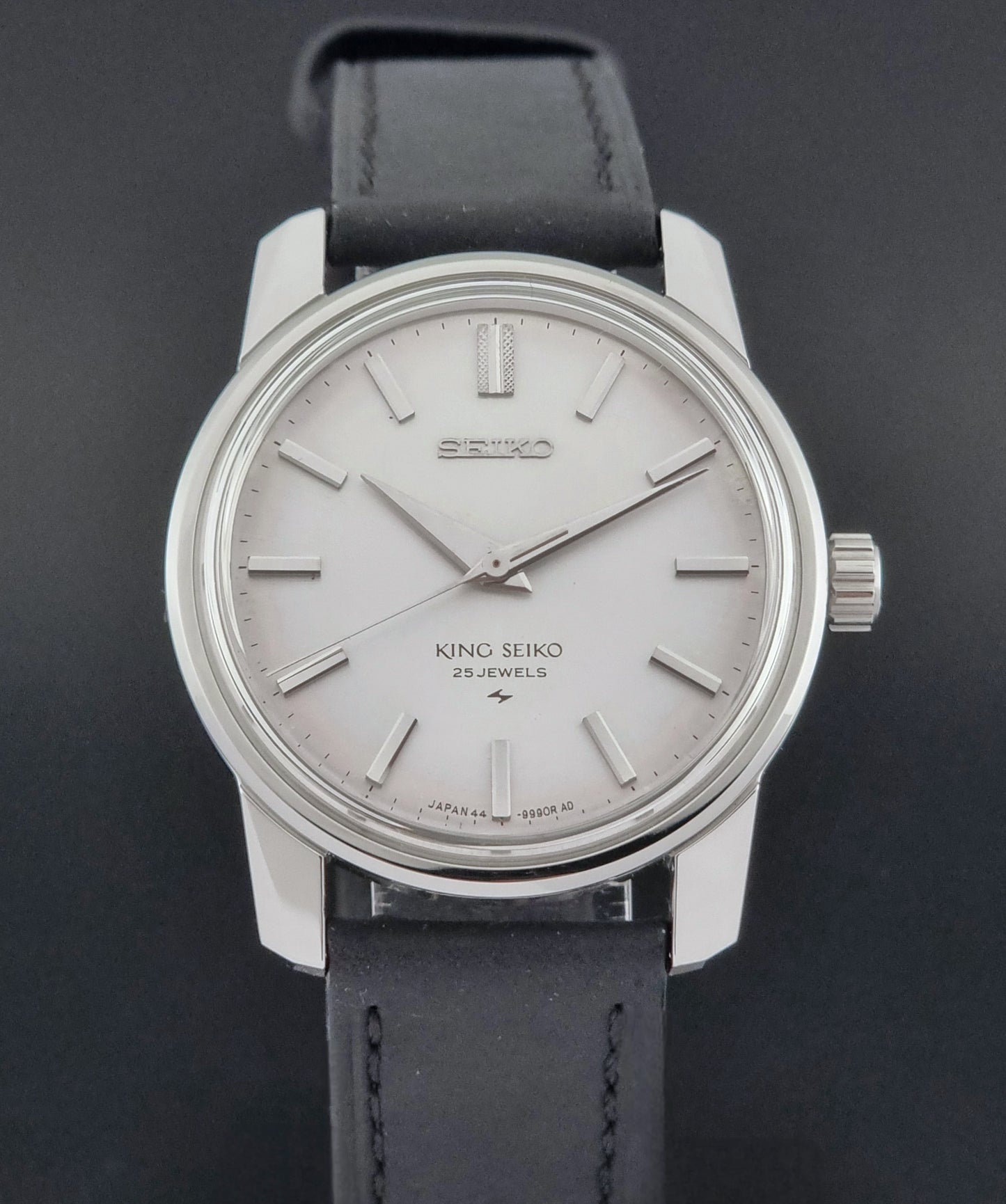 Vintage King Seiko 44-9990 wristwatch with black leather strap and silver case on a dark background close front view