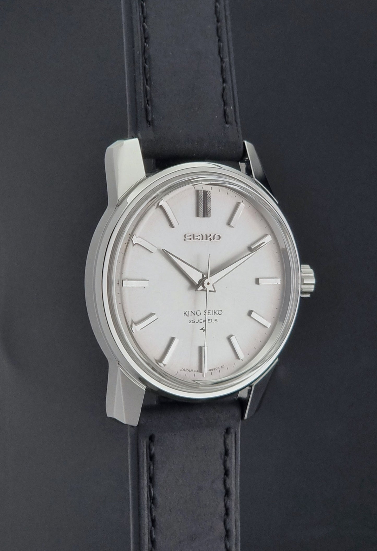 Vintage King Seiko 44-9990 wristwatch with black leather strap and silver case on a dark background side profile view