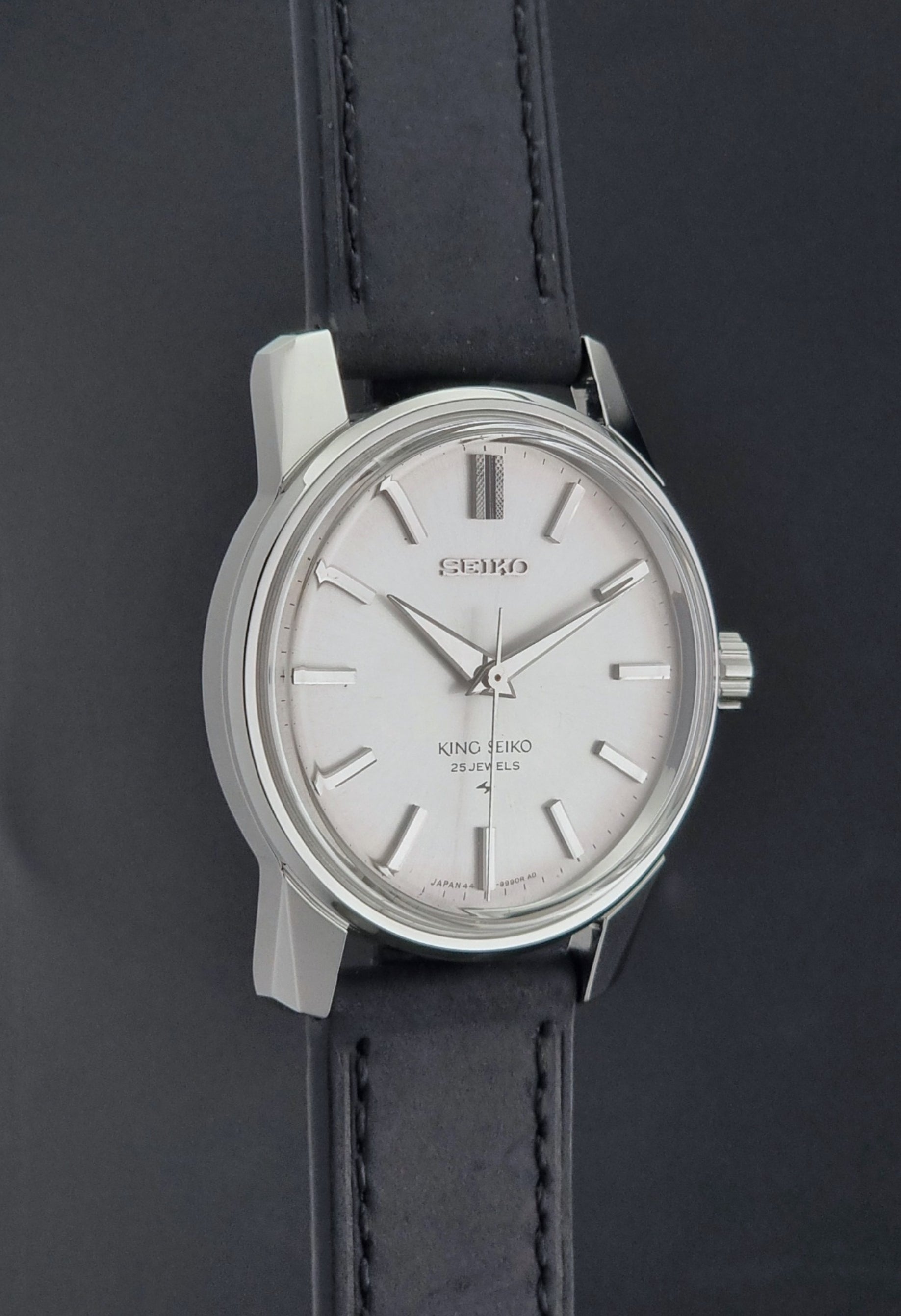 Vintage King Seiko 44-9990 wristwatch with black leather strap and silver case on a dark background side profile view
