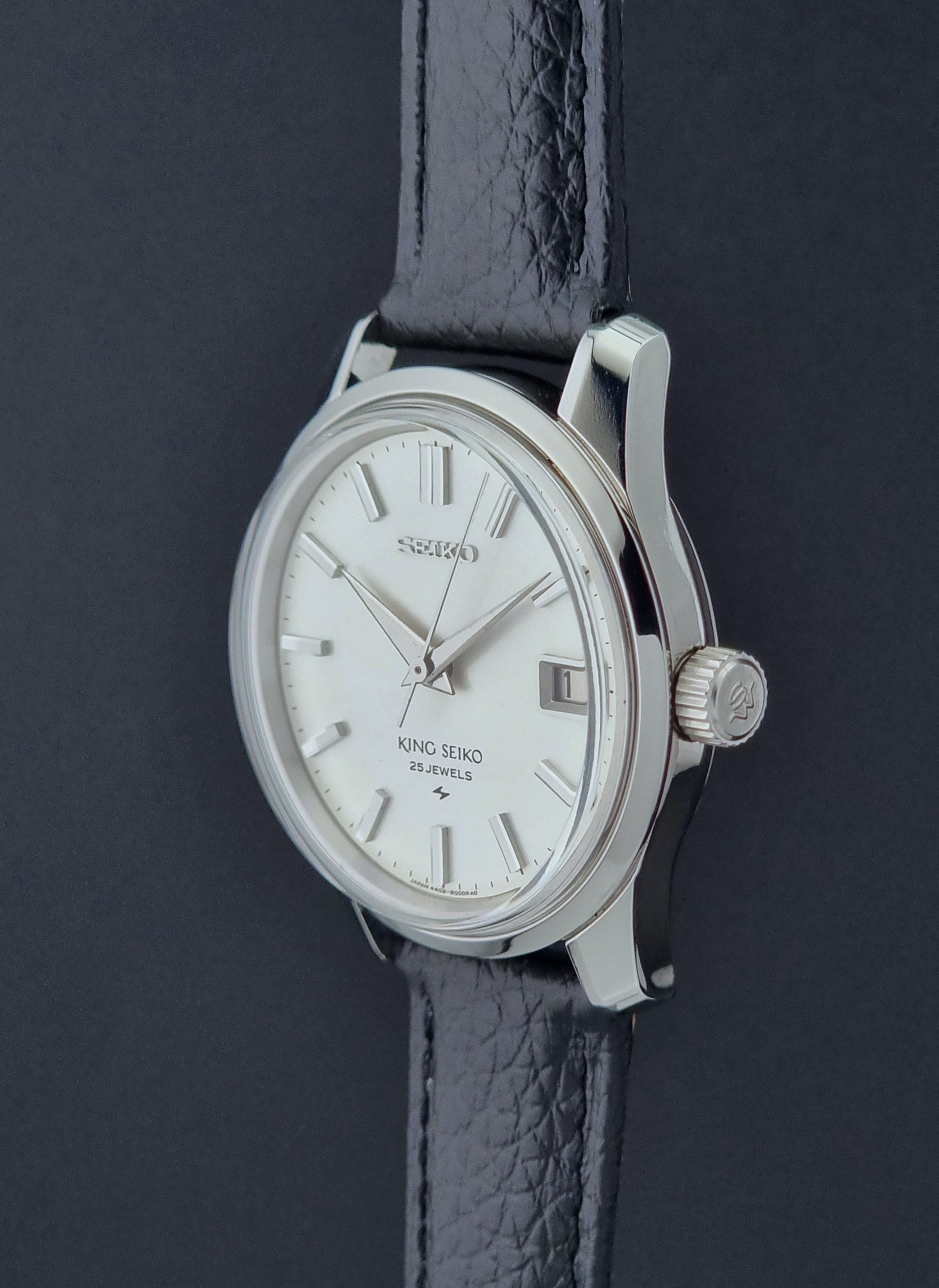 Vintage King Seiko Wristwatch 4402-8000 on a black leather strap on a dark background profile view crown side